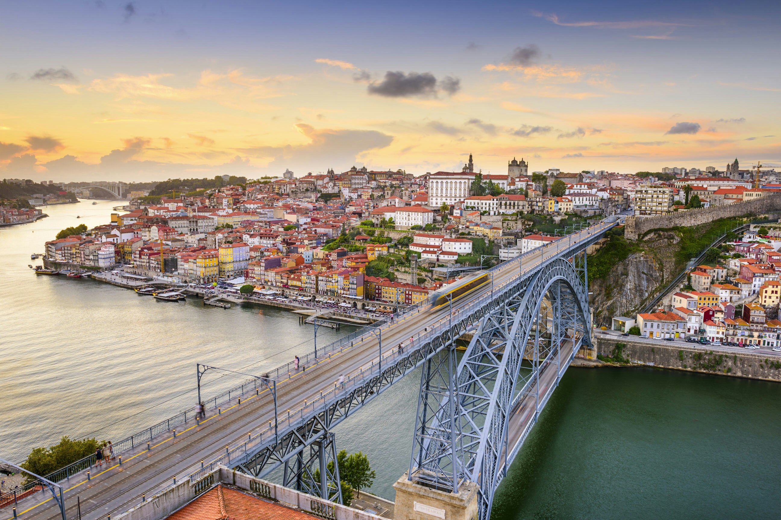 The Dom Luis Bridge stretches out over the rippling waters of the Douro river at sunset.