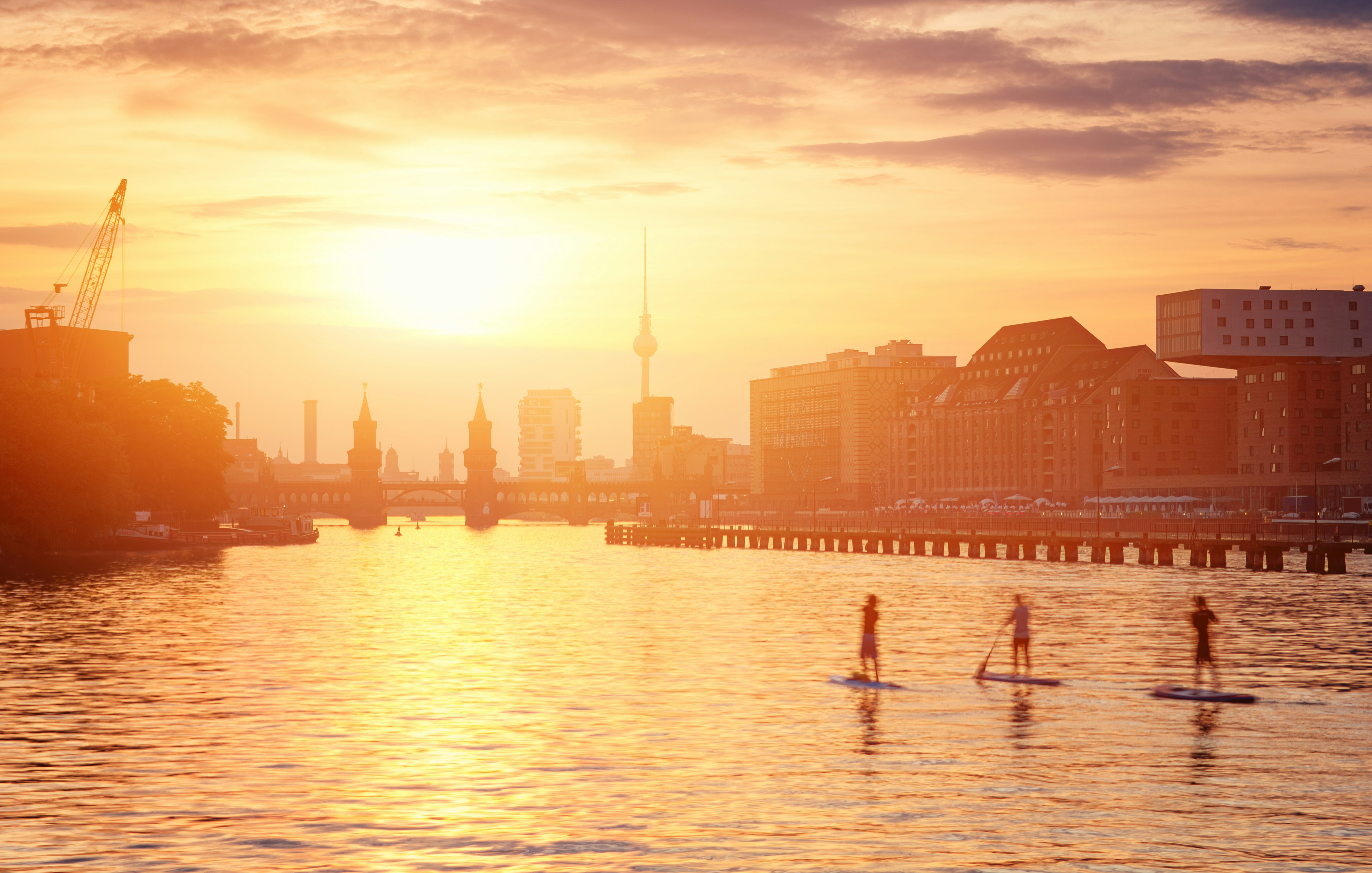 People paddle board down a river in Berlin at sunset; Where to travel with your tweens and teens