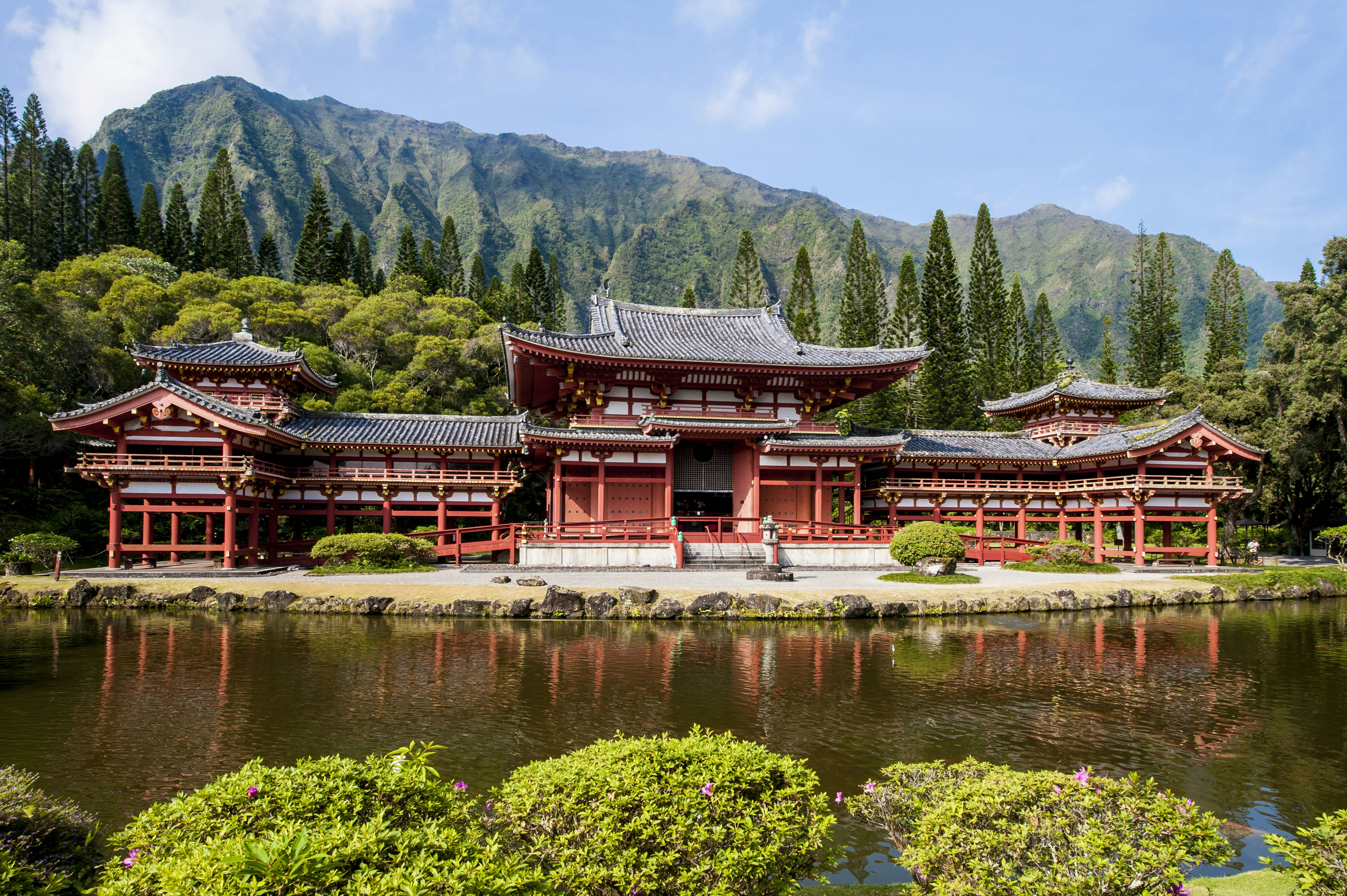 A Japanese temple, resplendent in reds and golds, is set in a groomed park at the base of a mountain in O'ahu