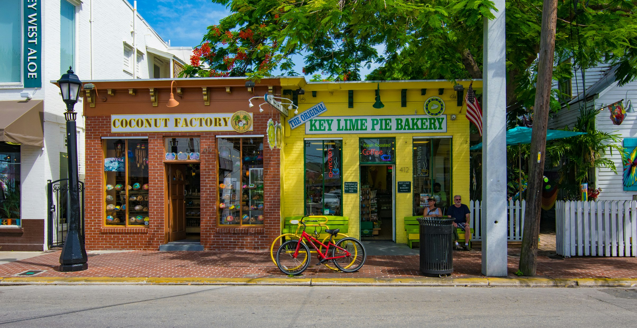 Färgglada skyltfönster som heter Coconut Factory och Key Lime Pie Bakery med två cyklar parkerade framför