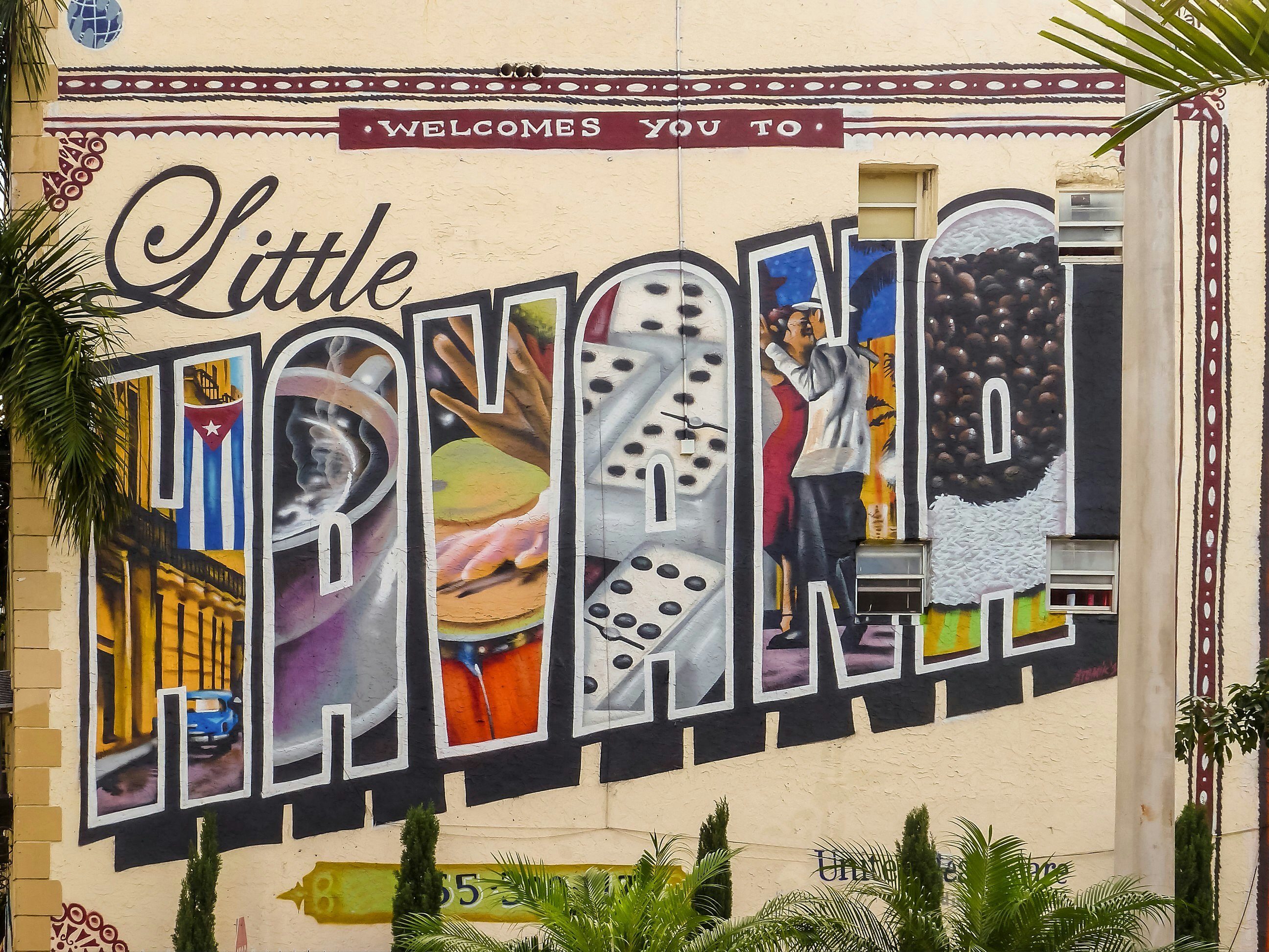 A mural on the side of a wall spelling 'Little Havana' Each of the letters of Havana has a different Cuban-themed scene painted inside.