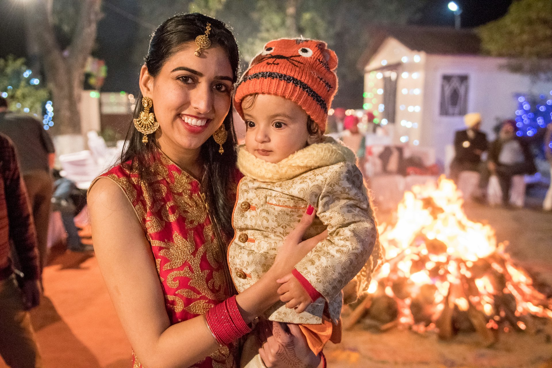 A woman and her son stand in front of a fire at a Lohri festival in Punjab, India