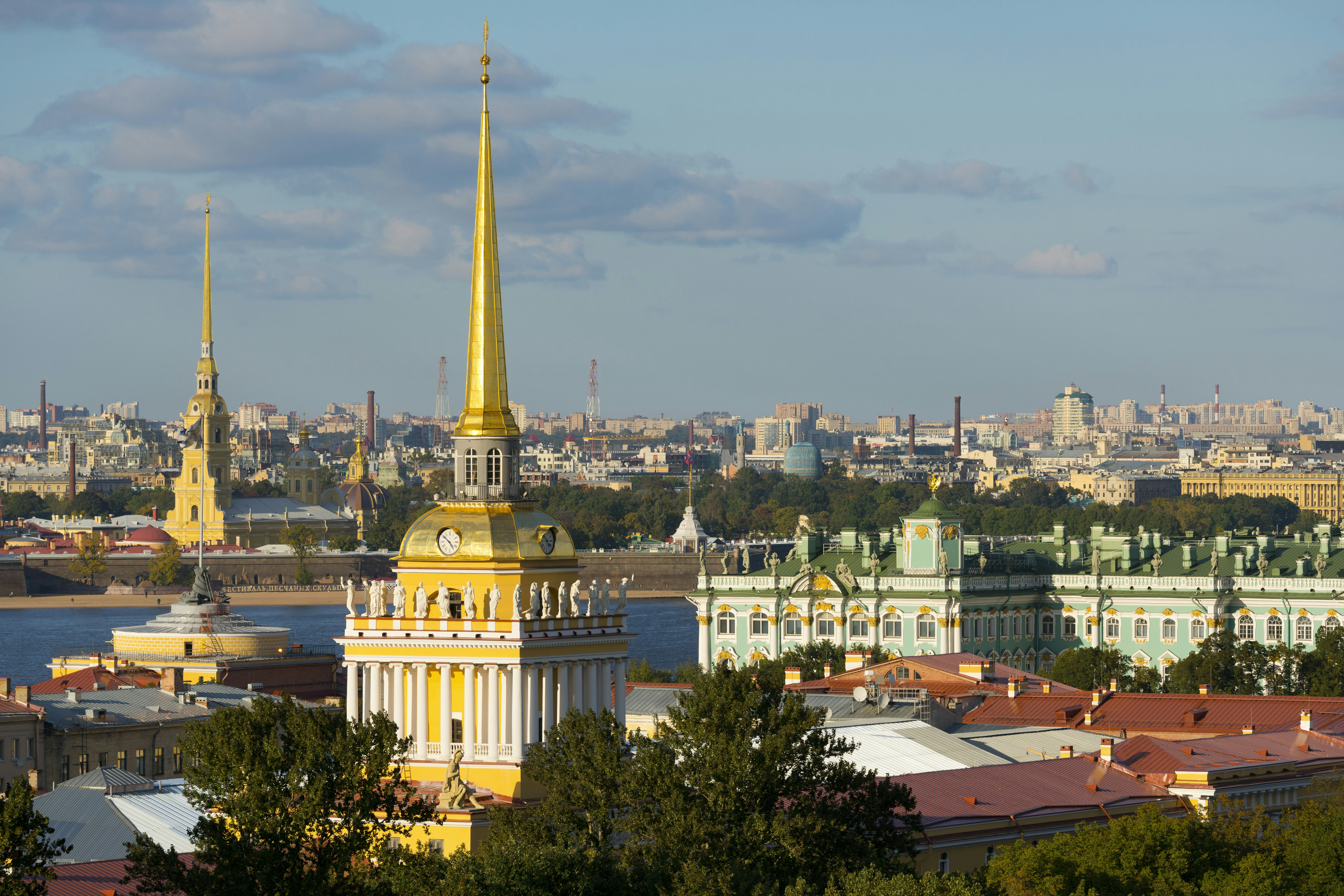An aerial view of St Petersburg's landmark architecture, with golden spires and ornate facades visible beneath a blue sky
