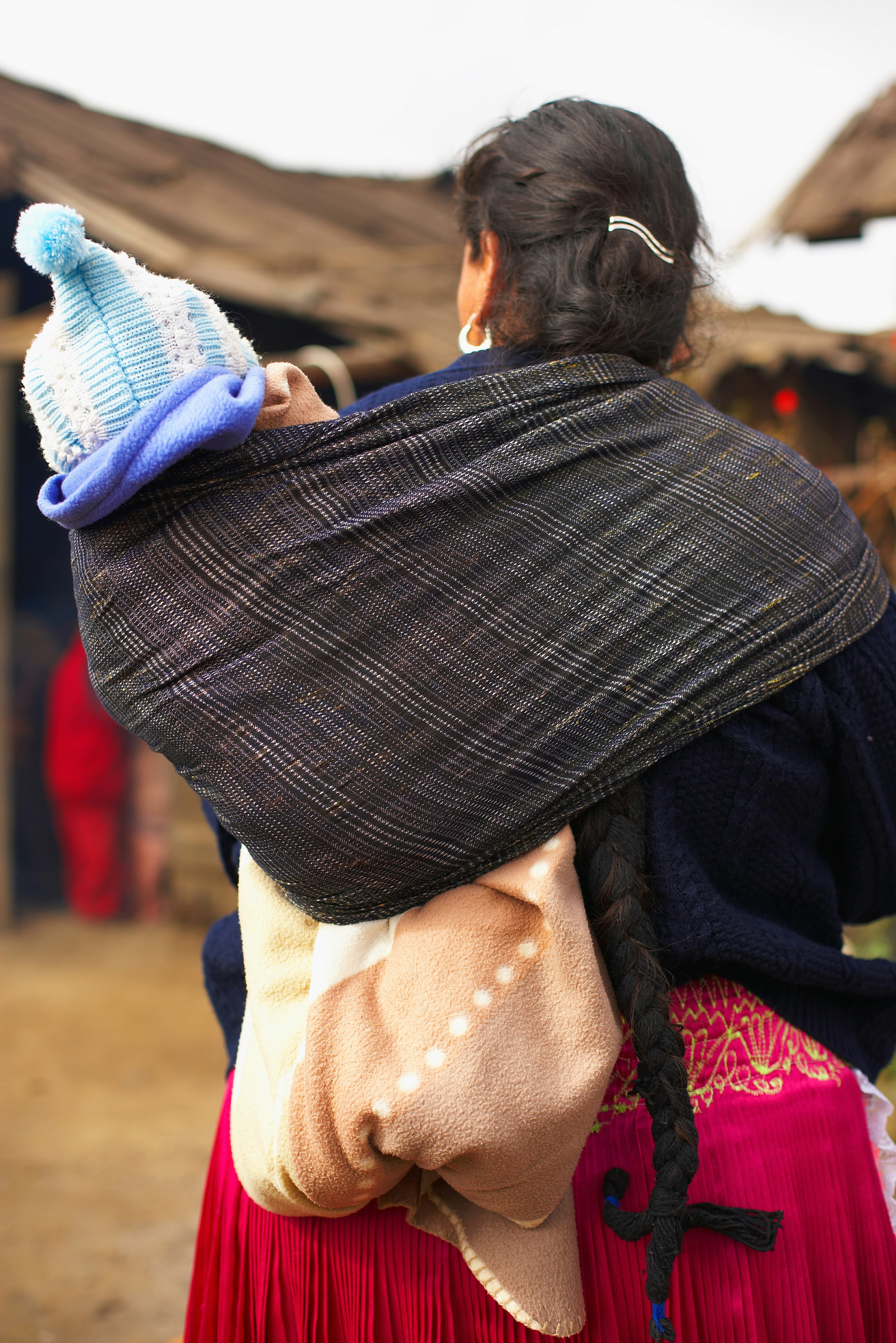 A woman carrying a baby using a rabozo wrapped around her shoulder