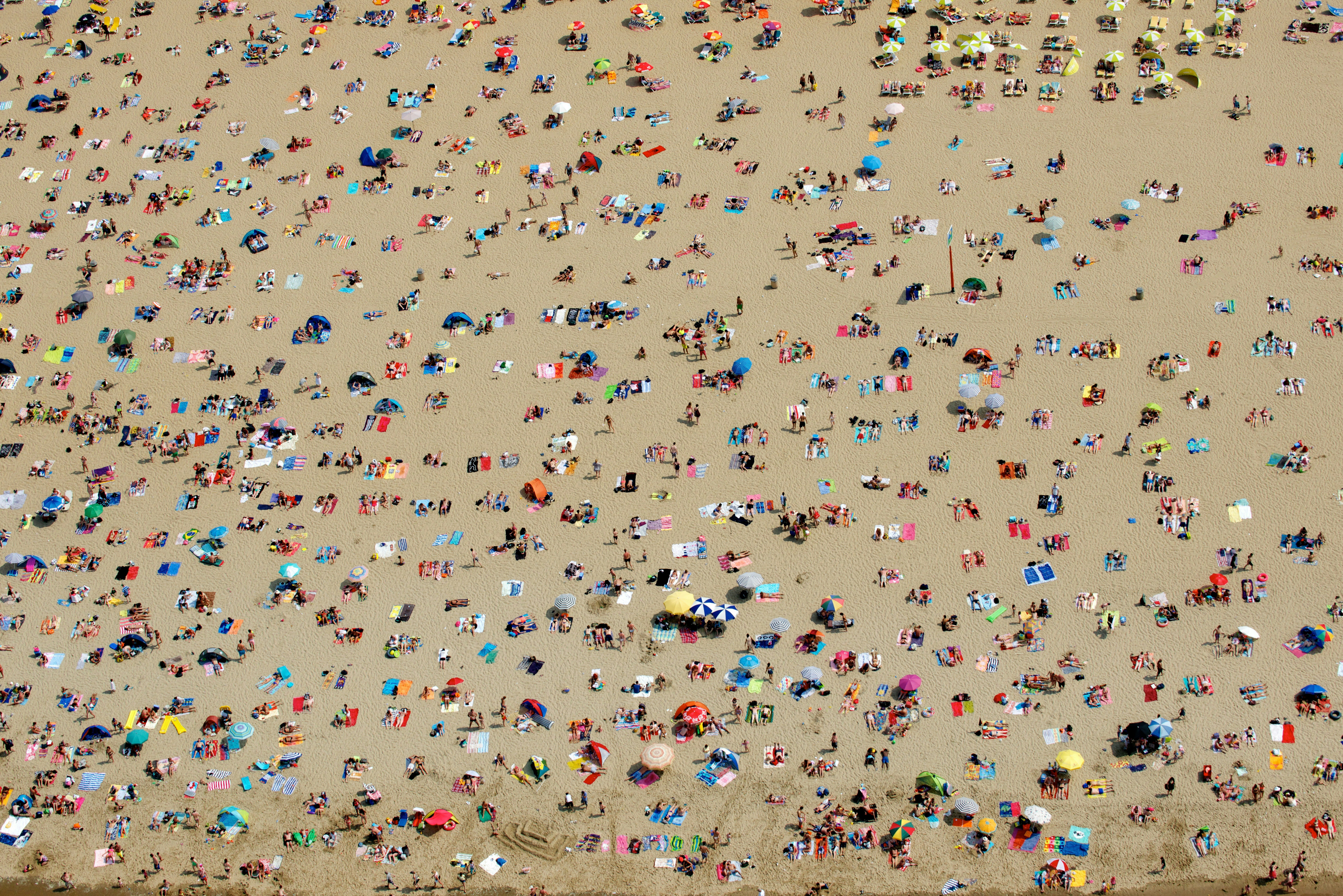An aerial shot of Zandvoort beach in Amsterdam. The golden sand is filled with bathers enjoying the sun.