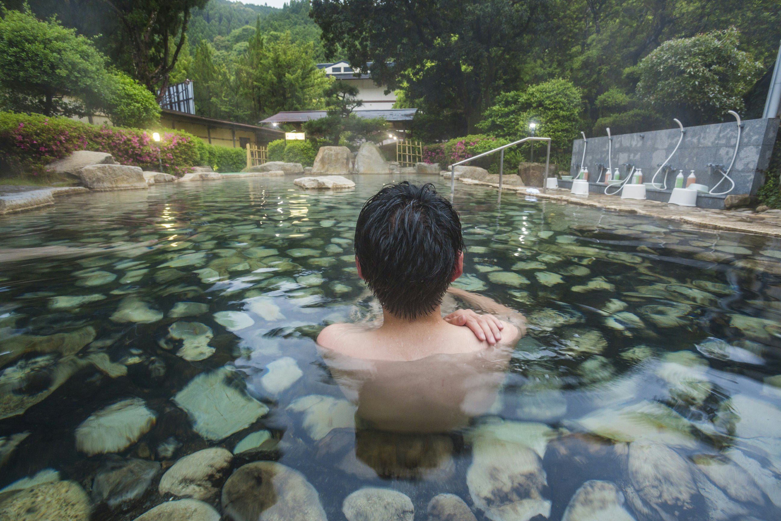 A person sits in an open air hot spring bath in Japan.