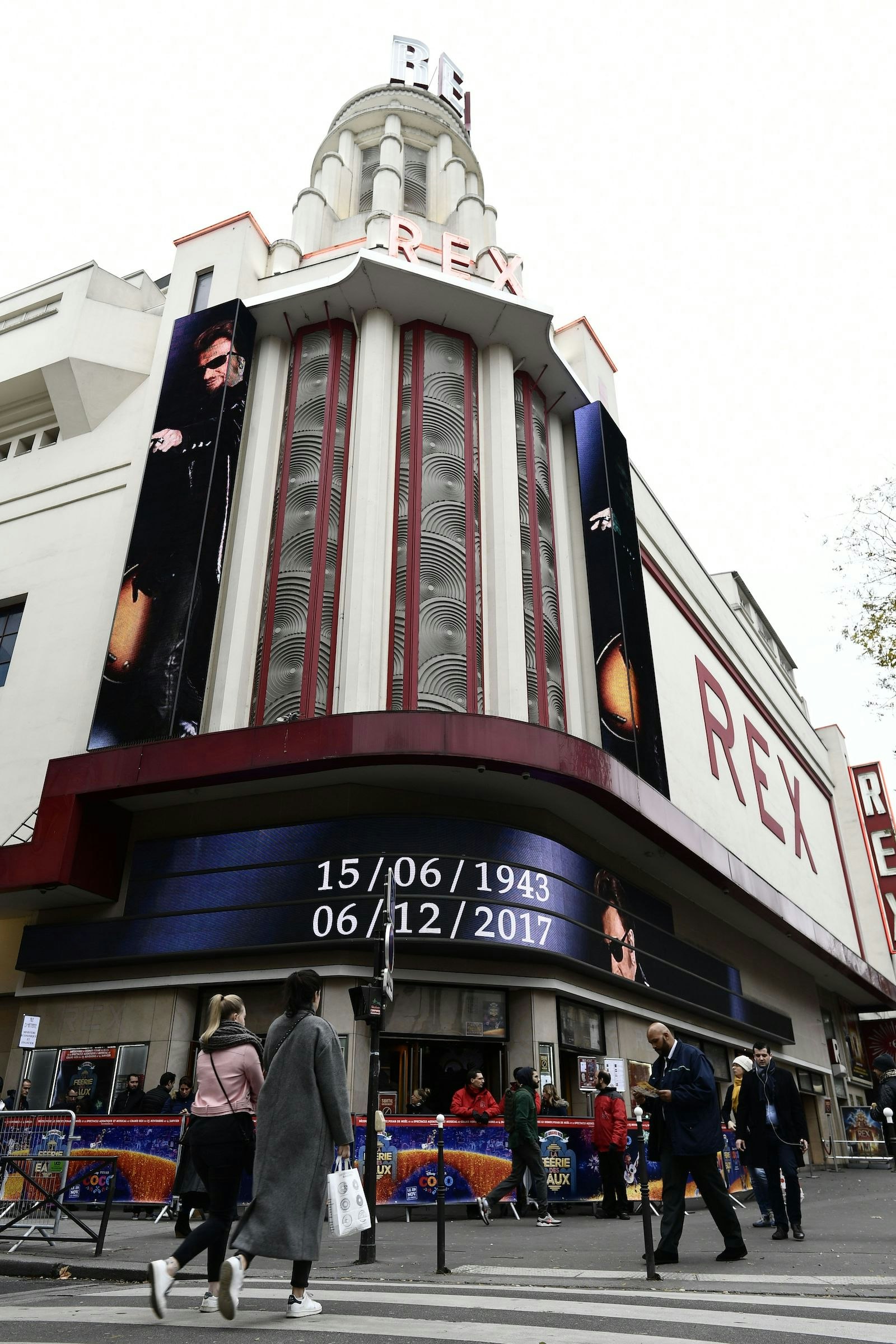 People walk past the Grand Rex cinema, bearing on its facade "15/06/1943" and "06/12/2017", the date of birth and death of late French singer and actor Johnny Hallyday, on December 6, 2017, in Paris. 