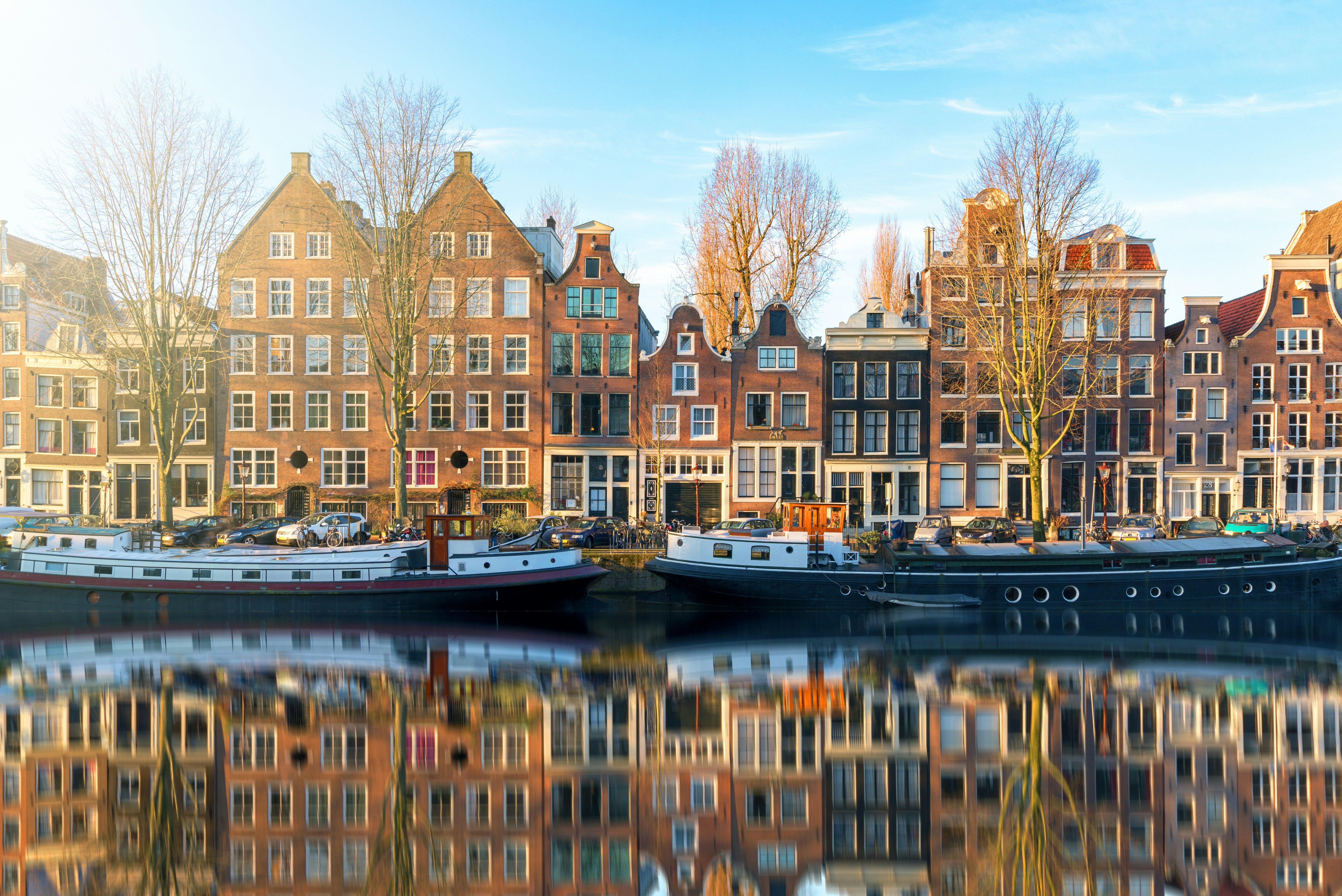 Traditional merchant houses line a canal in Amsterdam on a cloudless winters morning