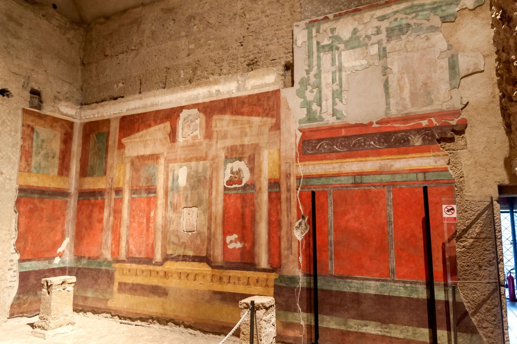 Crumbling red and green frescoes on the walls of the House of Augustus in Rome
