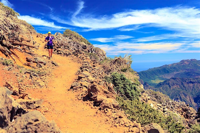A woman walks along a mountaintop dirt path on La Palma, Canary Islands