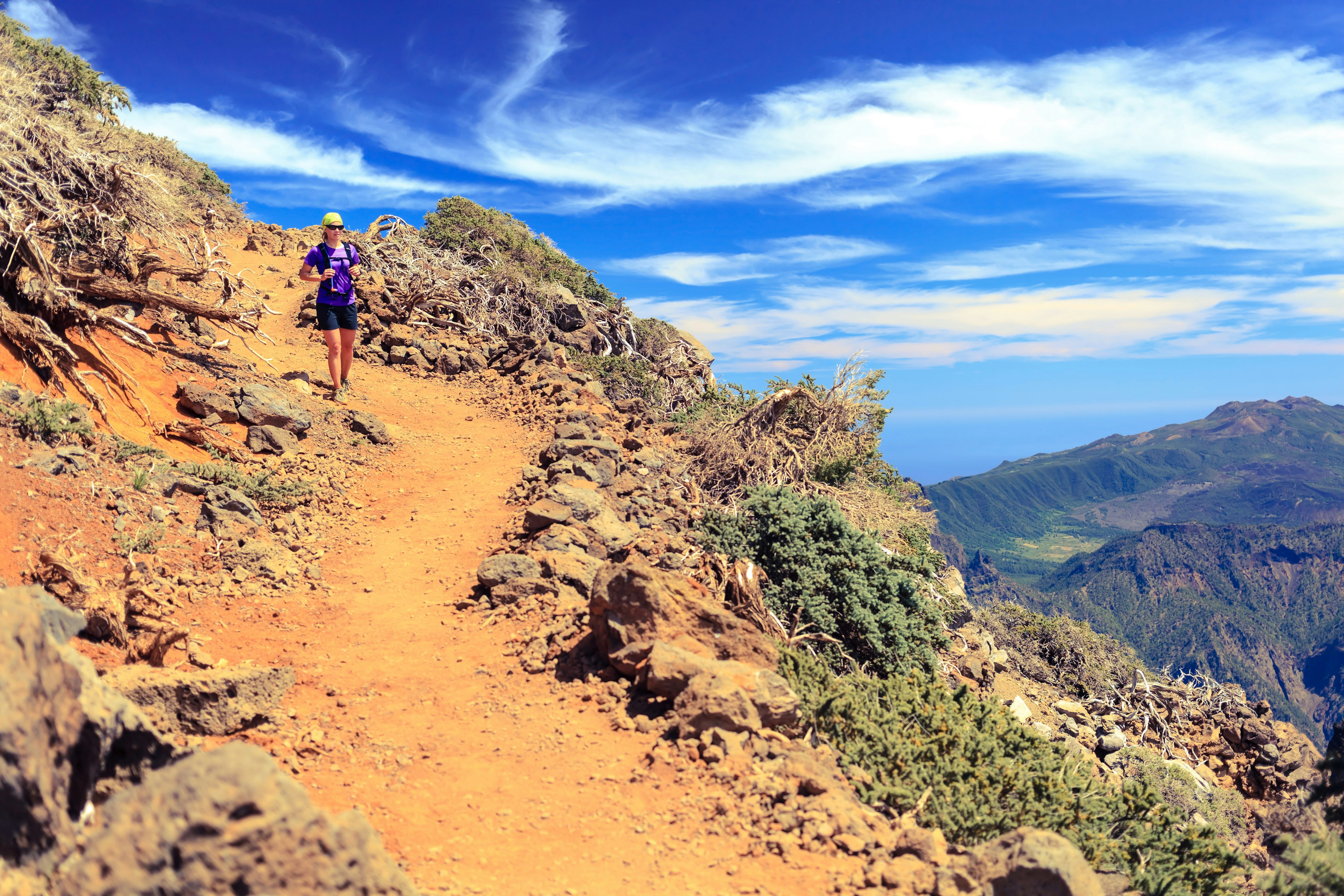 A woman walks along a mountaintop dirt path on La Palma, Canary Islands