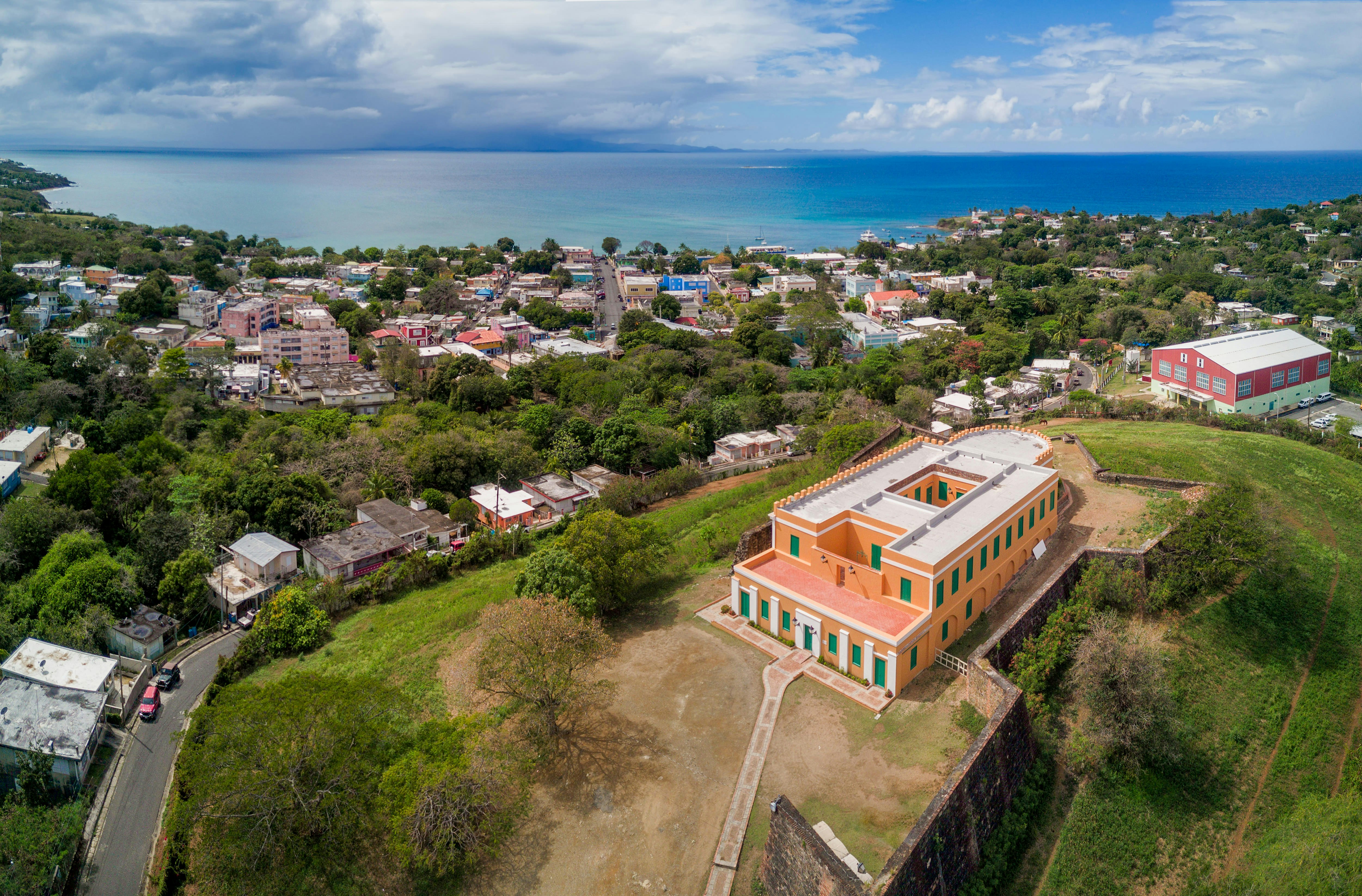 An aerial view of a candy-colored fort, with a backdrop of an oceanside town