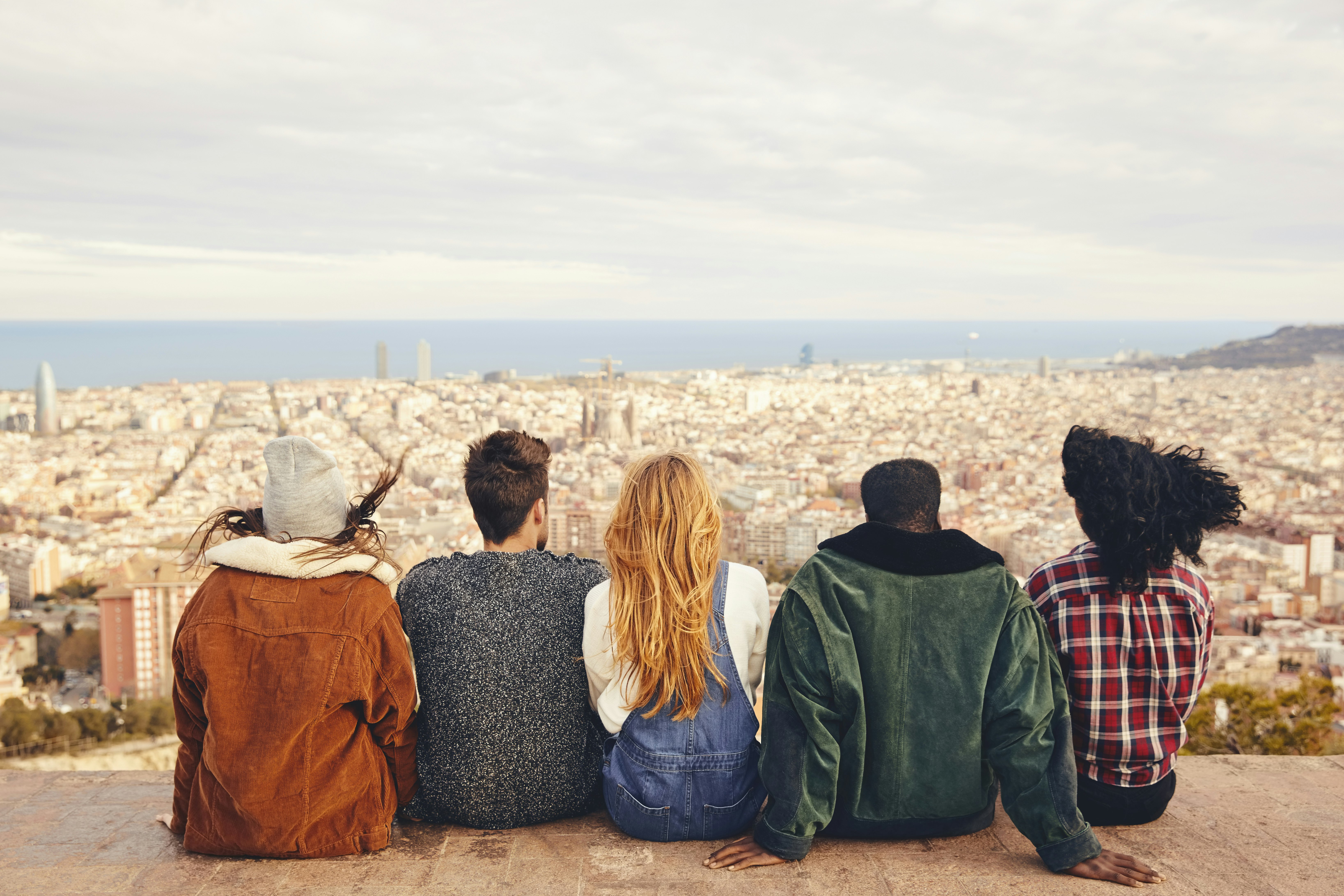 Five people sitting on building terrace overlooking the cityscape of Barcelona.