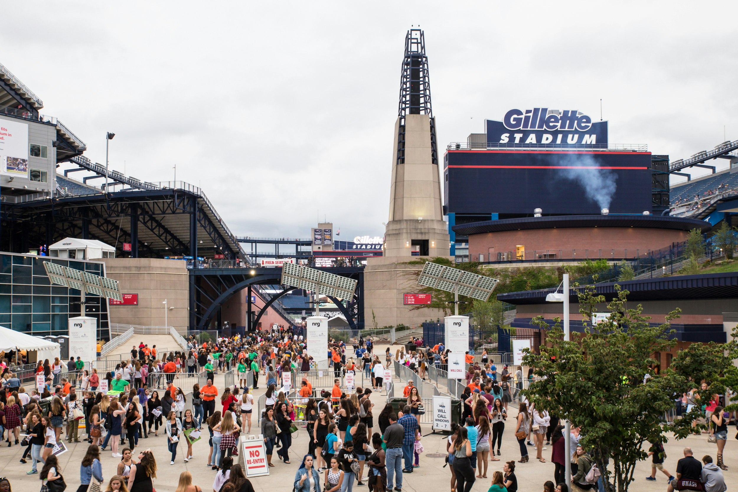 A group of people walk and stand around a concourse at Gillette Stadium in Foxborough; nfl cities travel