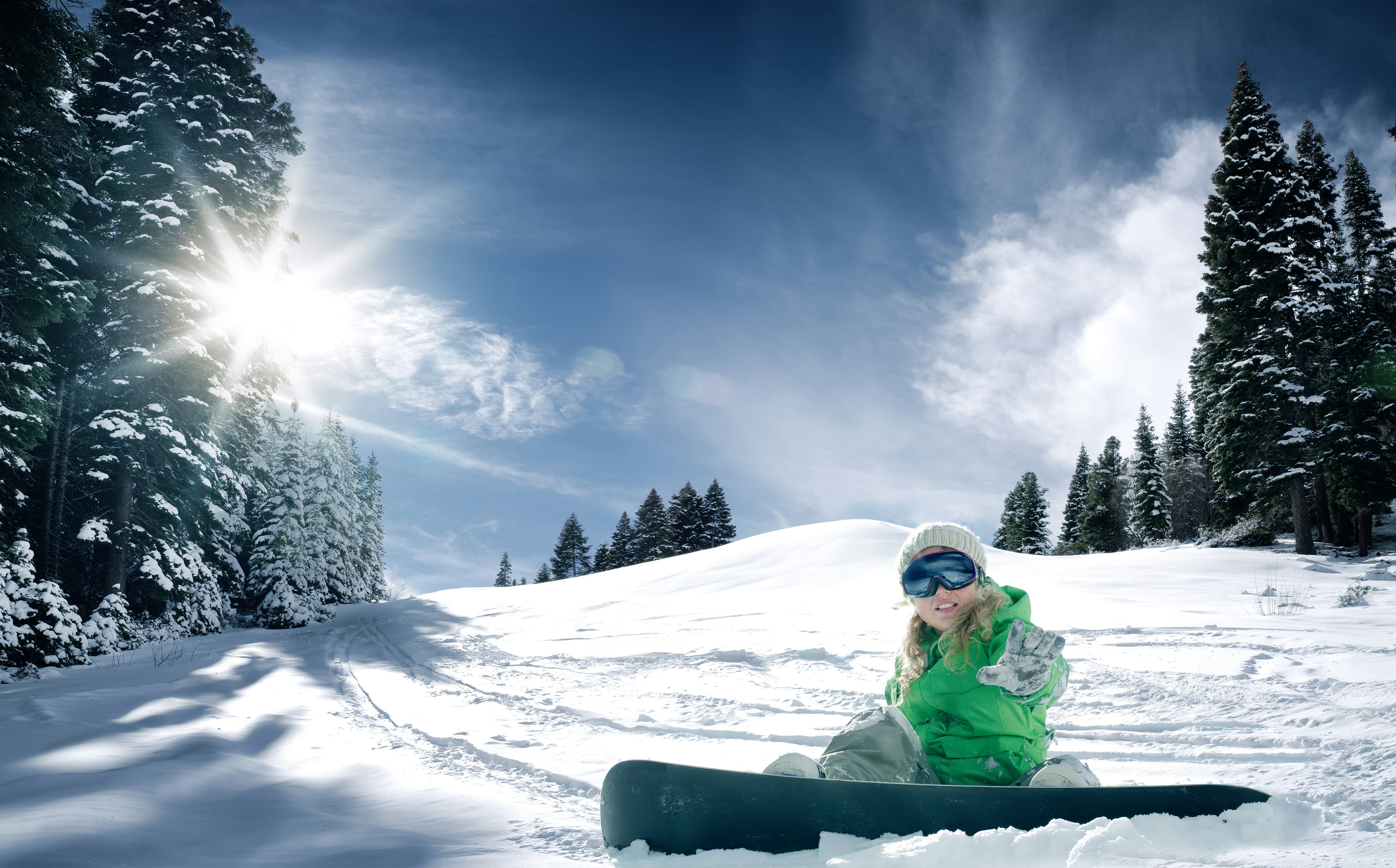 A girl rests on a snowy hill with her snowboard