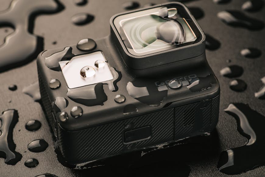 En GoPro-kamera står på en svart yta, täckt av vattenkulor. 