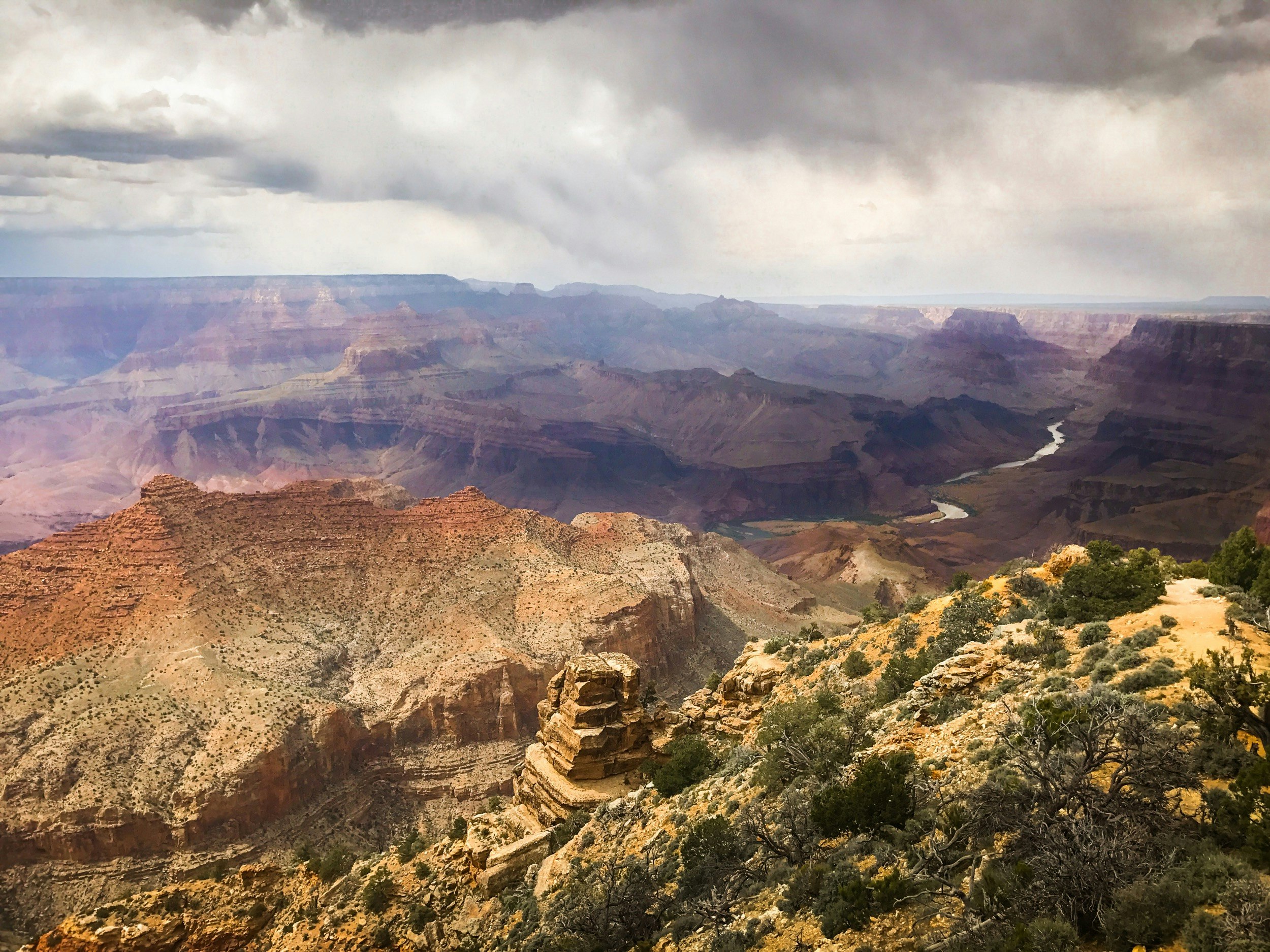 Looking down into the Grand Canyon from the rim, with striations and the river snaking off in the distance visible