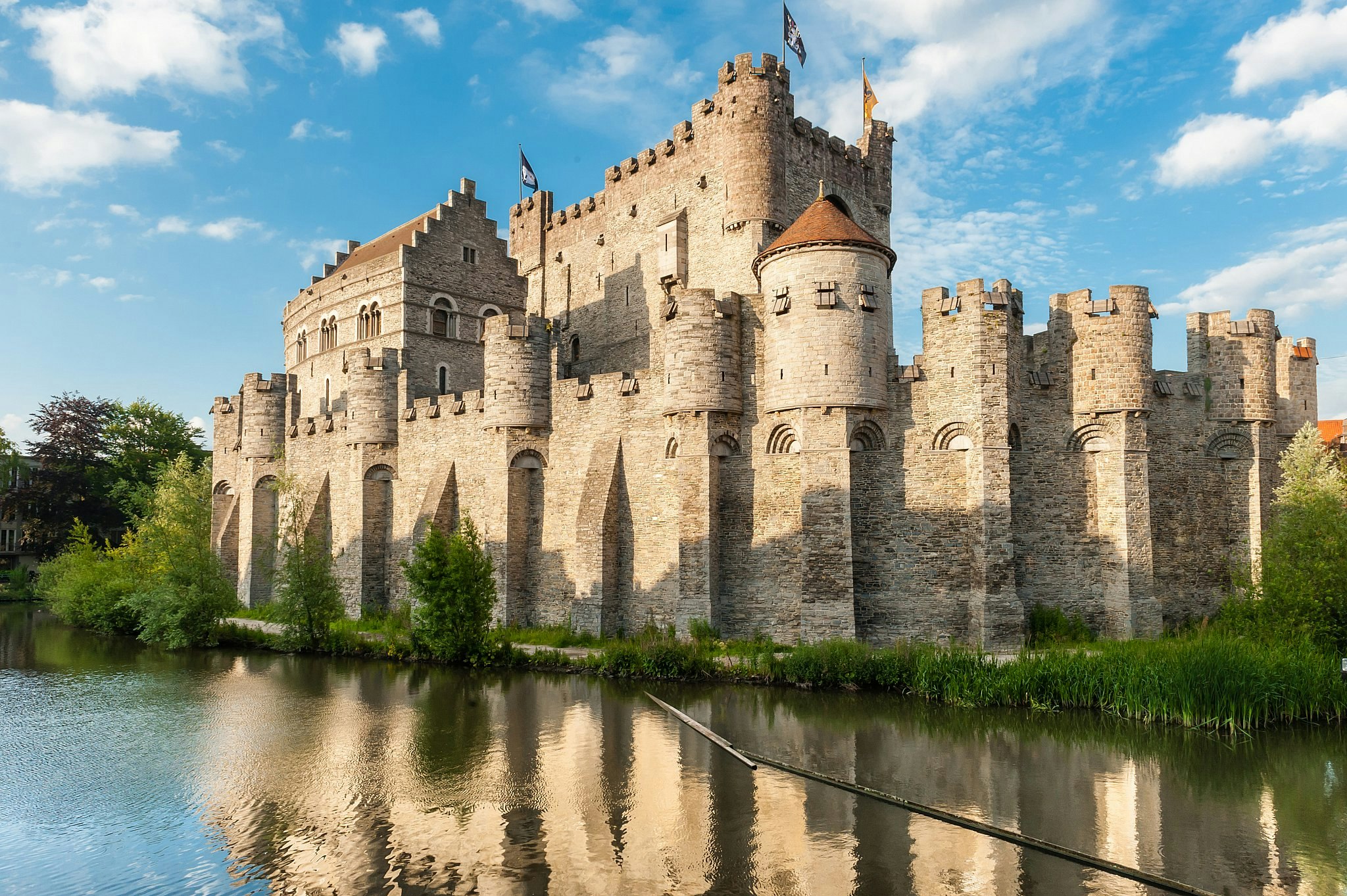 Gravensteen, a heavily fortified medieval castle surrounded by a moat in Ghent, with high walls and turrets.