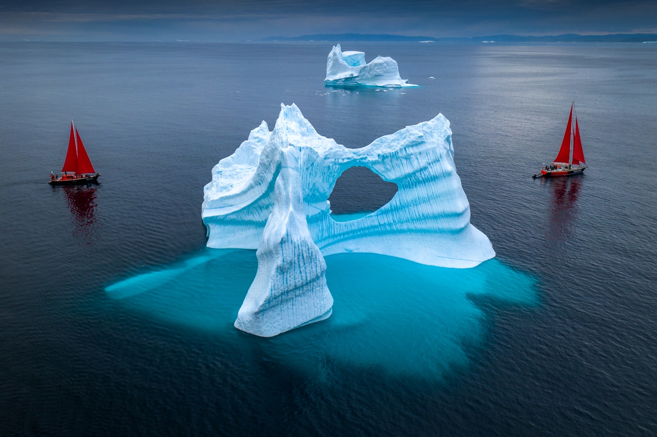 Ice caps in Greenland with two red sail boats