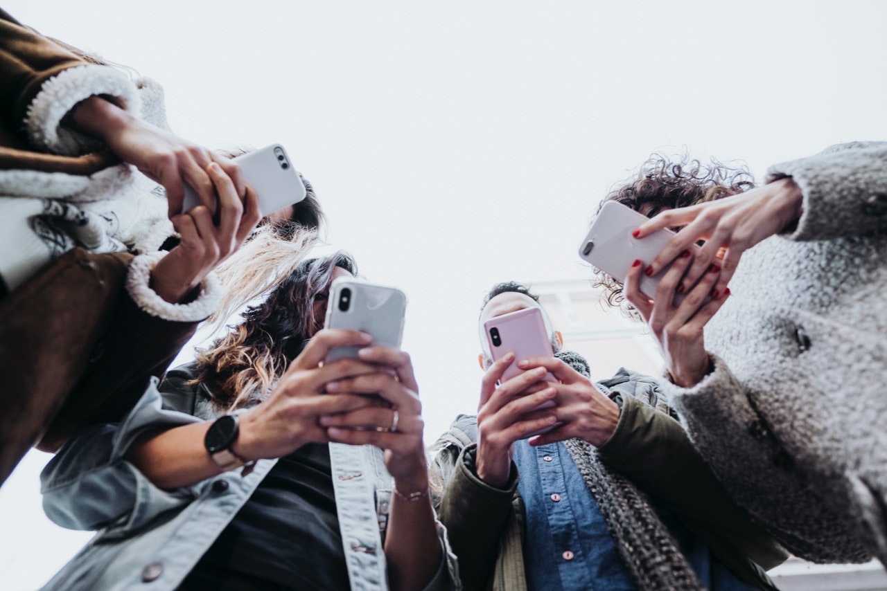 Group of friends in the street with smartphones