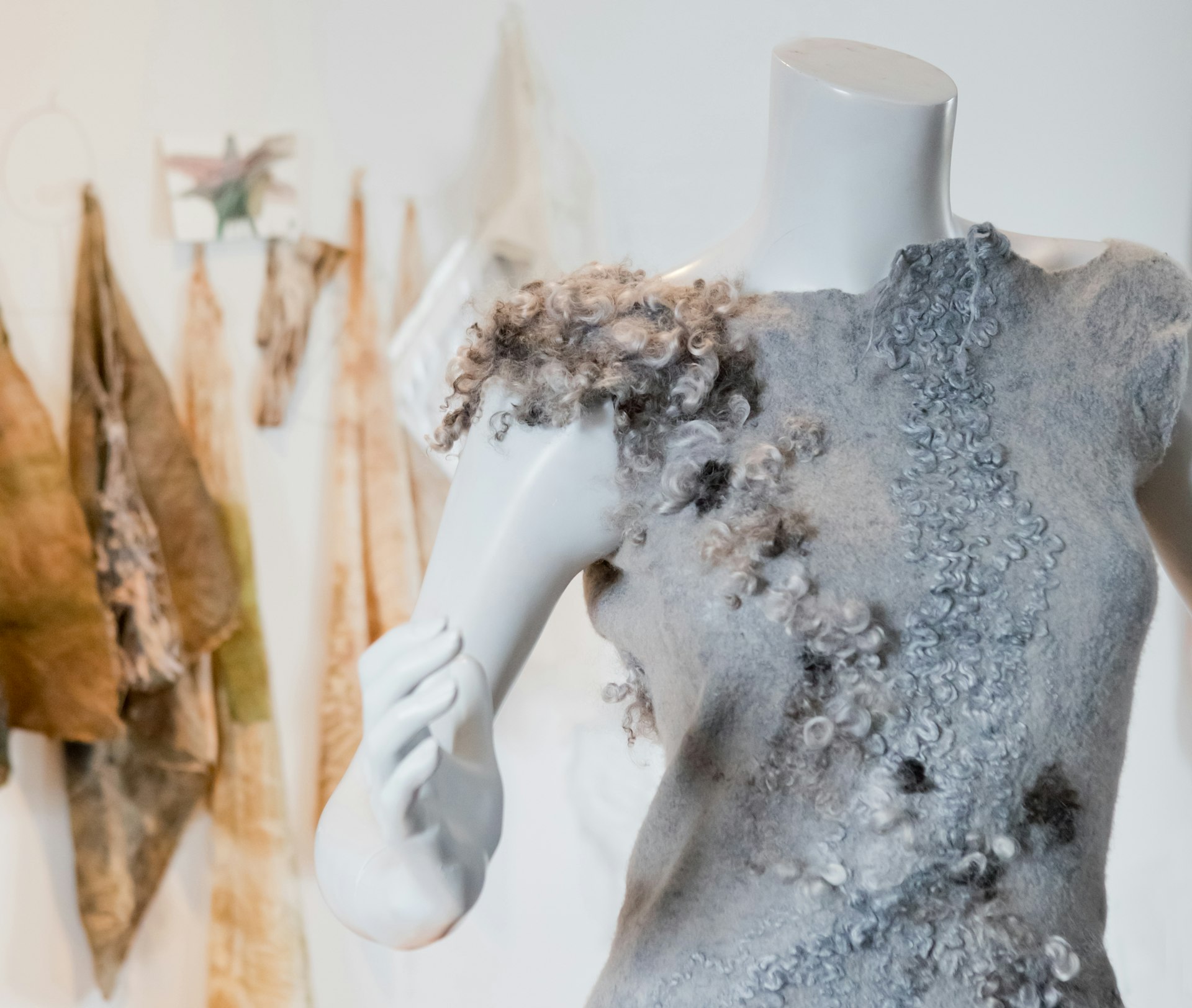 One of Celeste Malvar-Stewart's dresses shows the wide variety of colors and textures the come from working with natural wool. The dress is a soft grey with stream-like patches of curly or even fluffy, three-dimensional wool in browns, blacks, and deeper greys moving across the bodice