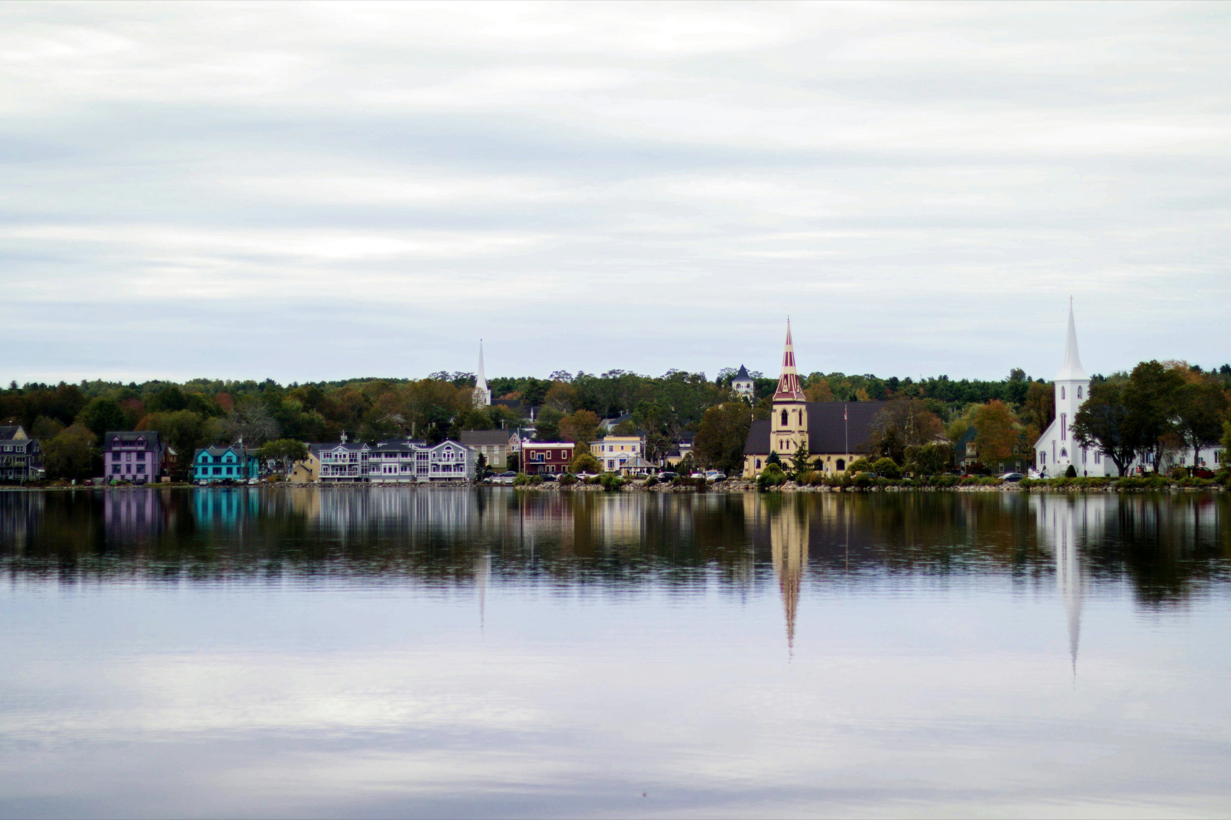 Looking across water, three church spires are reflected in the water in the foreground, as well as other smaller buildings near Halifax, Nova Scotia