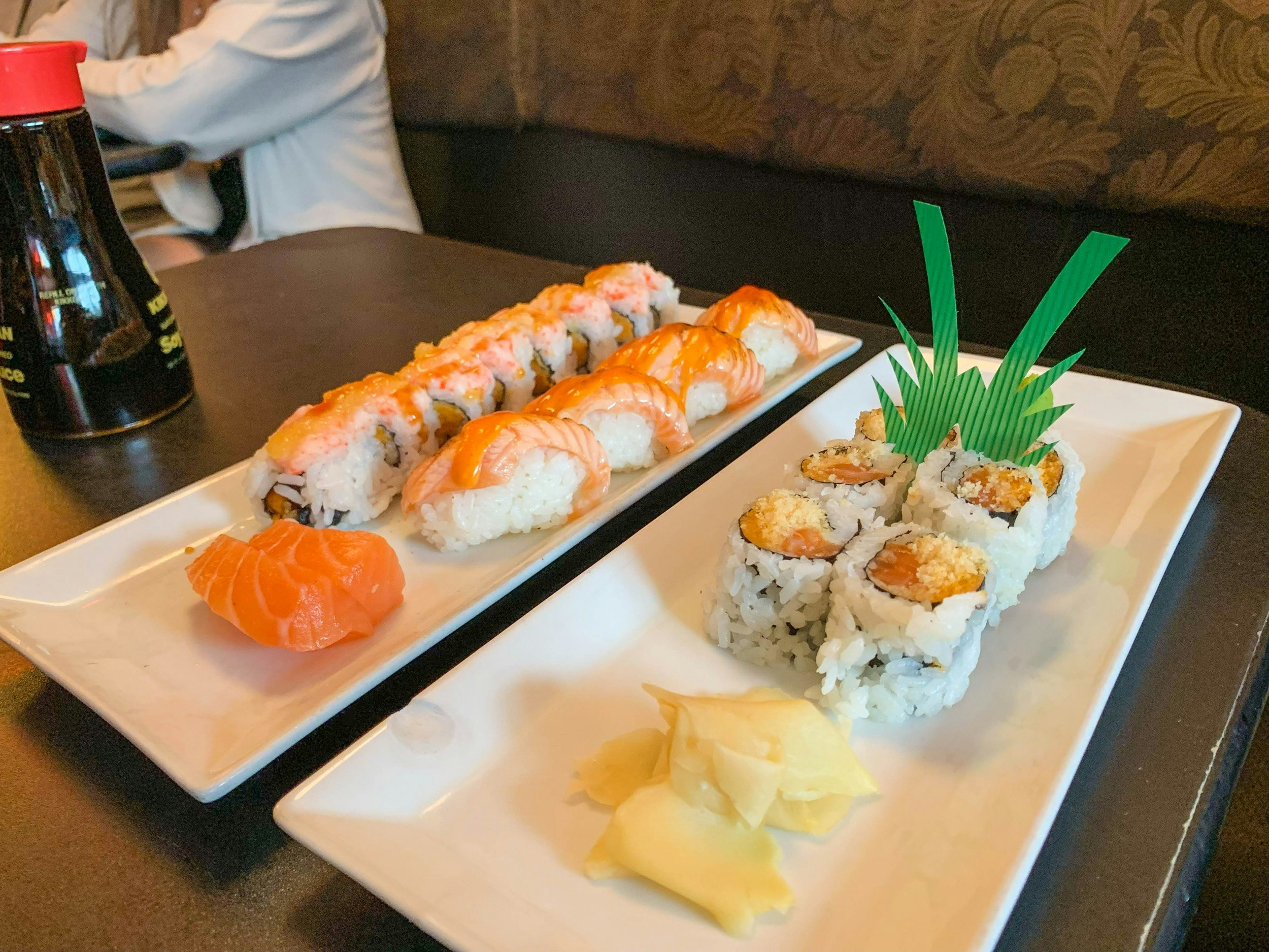 Two plates of sushi - one nigiri and one maki - are served with soy sauce