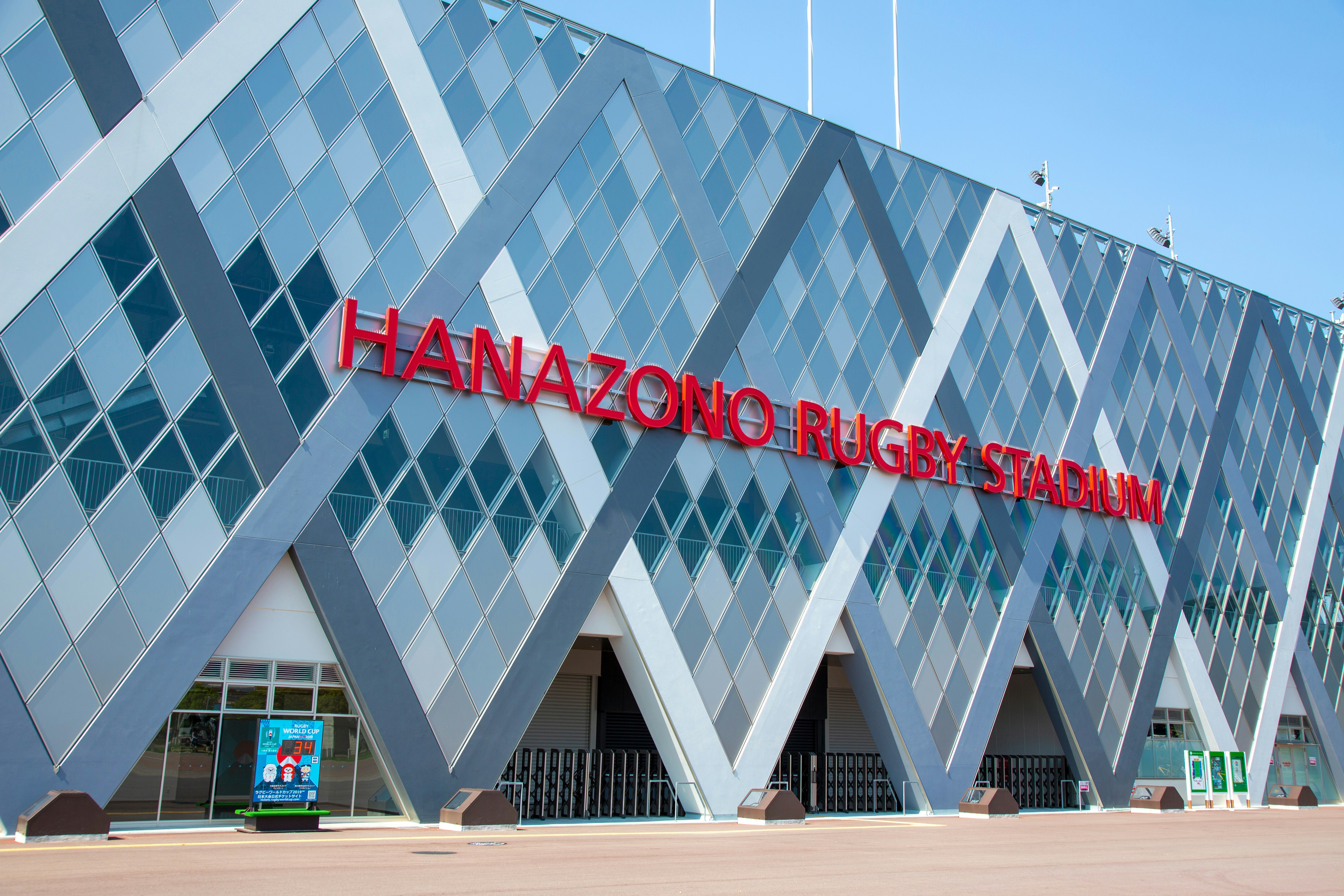 A large red sign that says "Hanazano Rugby Stadium" hangs on the side of the building. 
