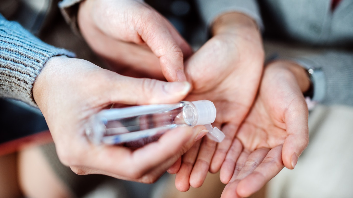 Adult squeezing hand sanitizer onto child's hands