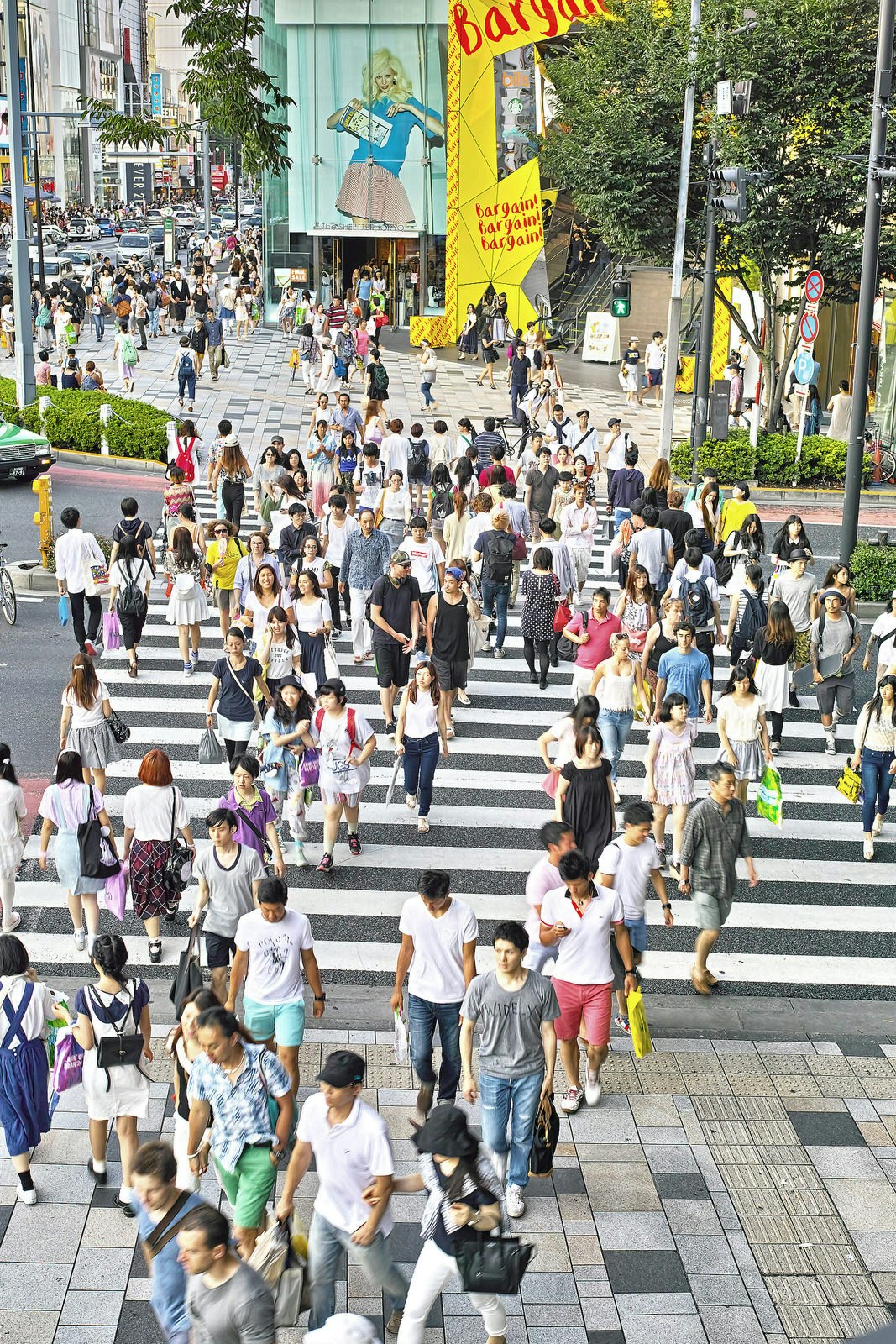 A large group of people walk across a crowded street in Harajuku shopping district 