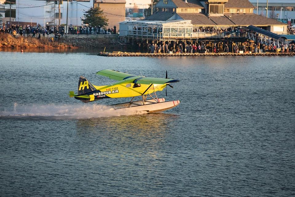 A yellow electric plane taking off over water in Richmond, Canada