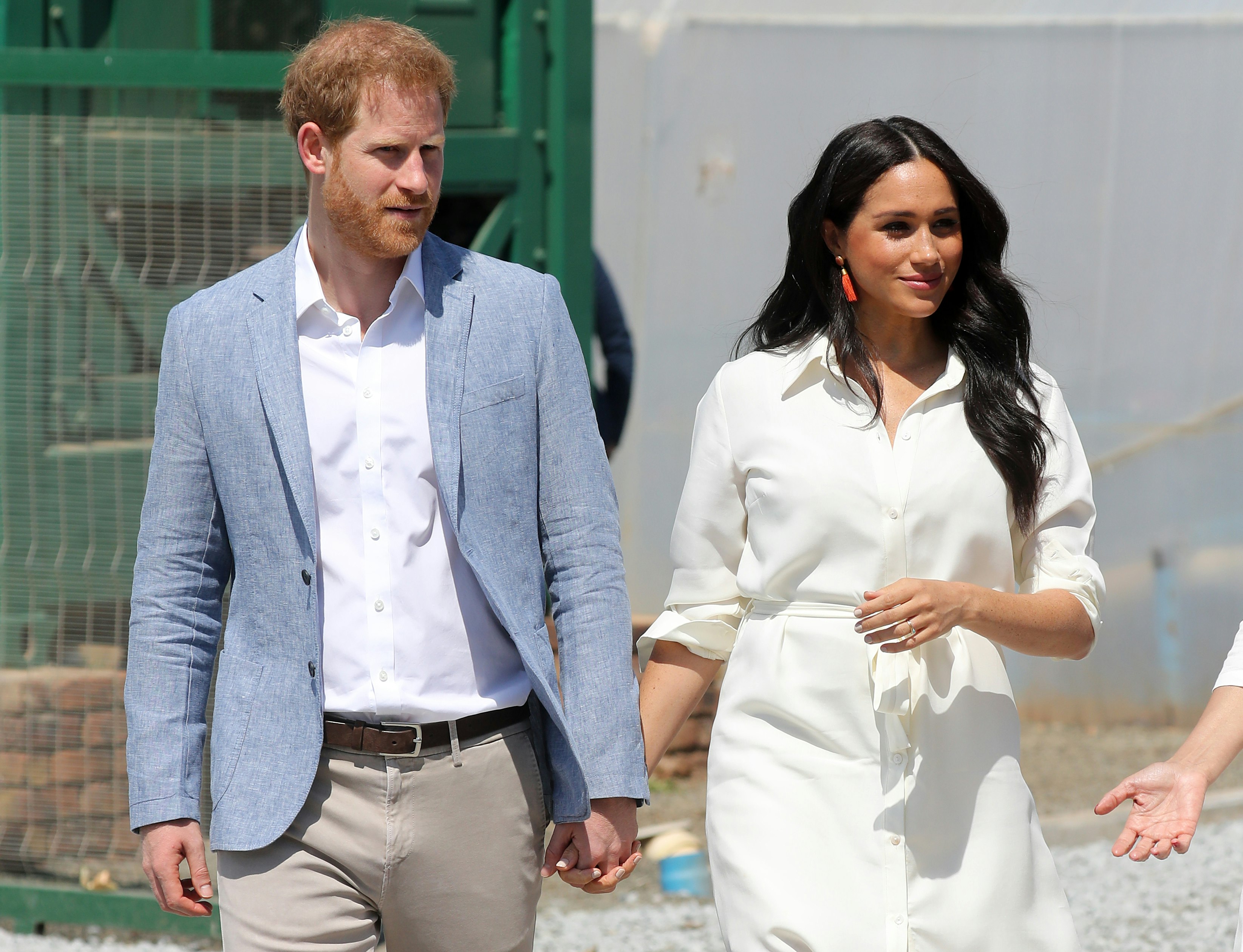 Prince Harry and Meghan Markle olds hands while visiting a Youth Employment Service building in South Africa.