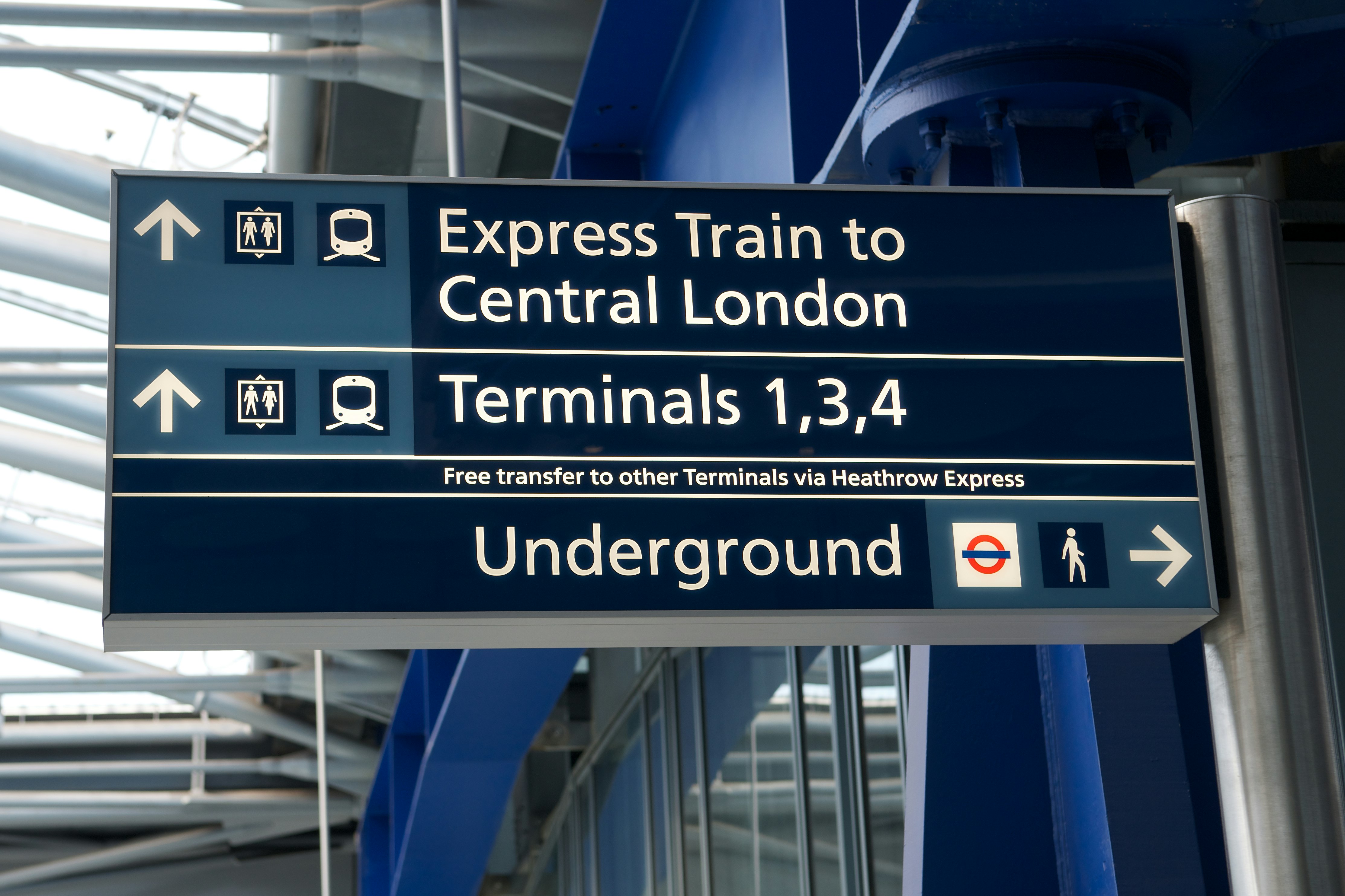 Blue and white sign with a series of icons and words 'express train to central London' 'Terminals 1,3,4' and 'Underground'