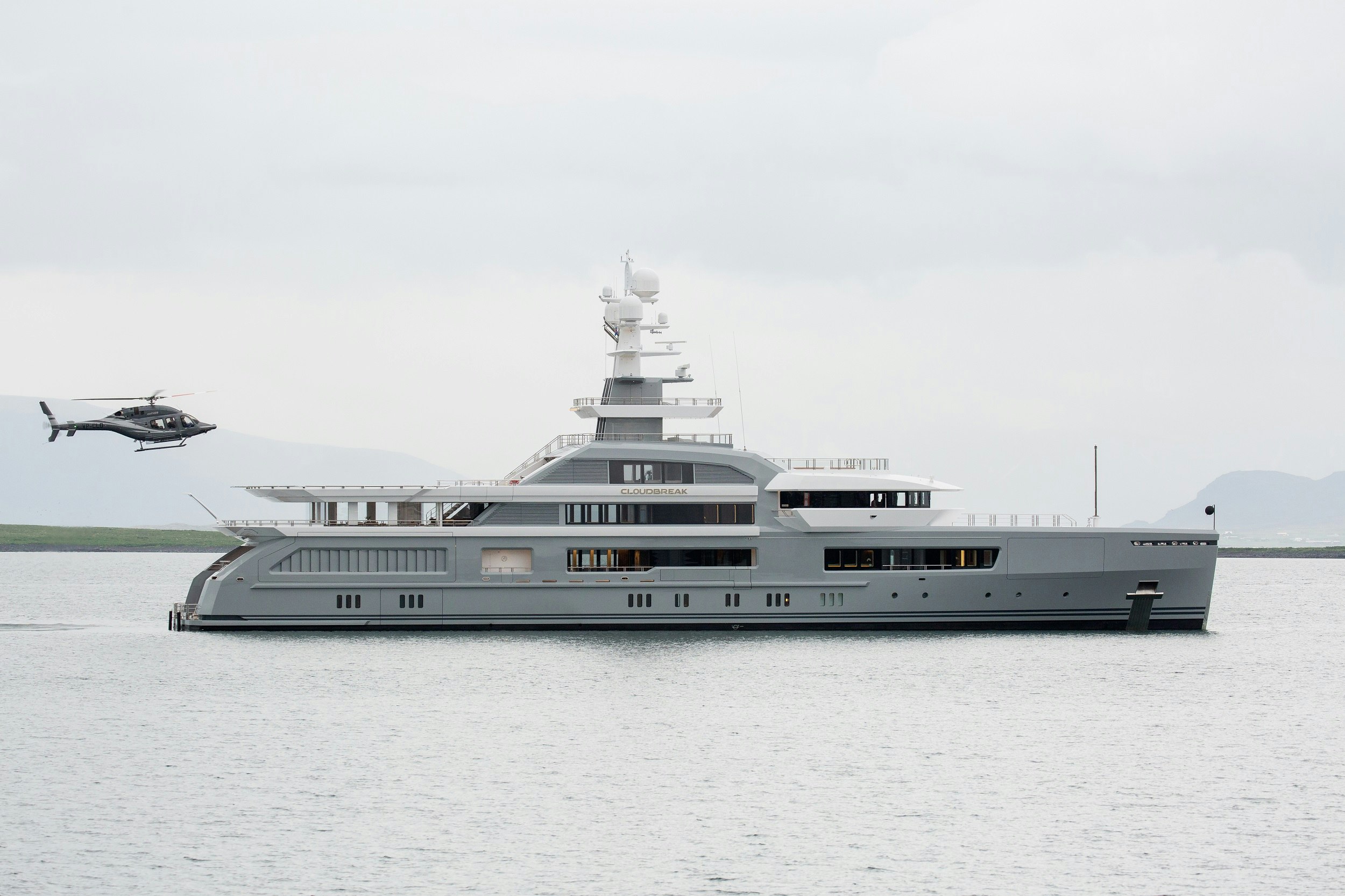 A helicopter coming in to land on the back of a large private yacht