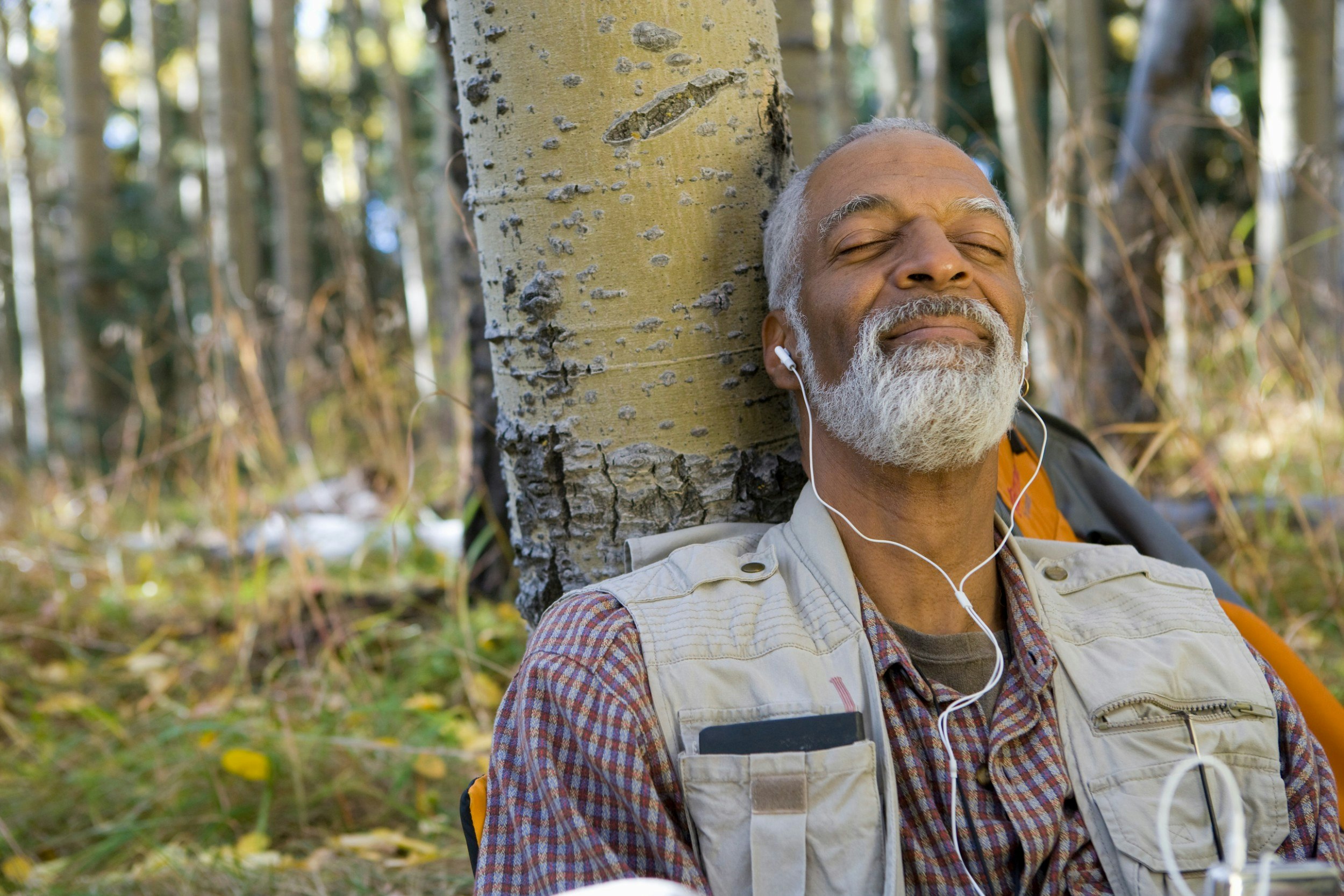 A hiker with a beard listening to music in the wood