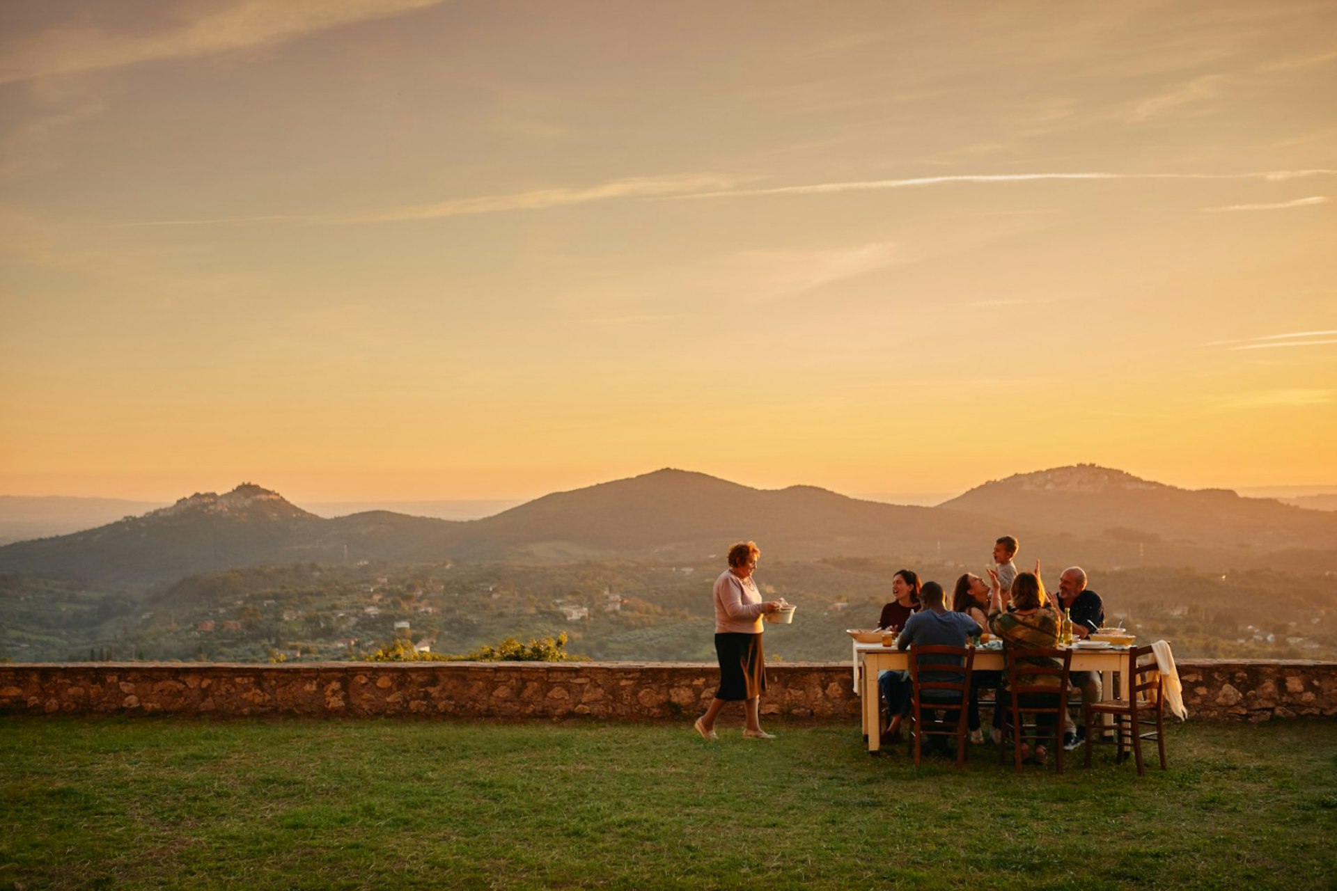 A group of friends sittig around a table in the distance in Italy