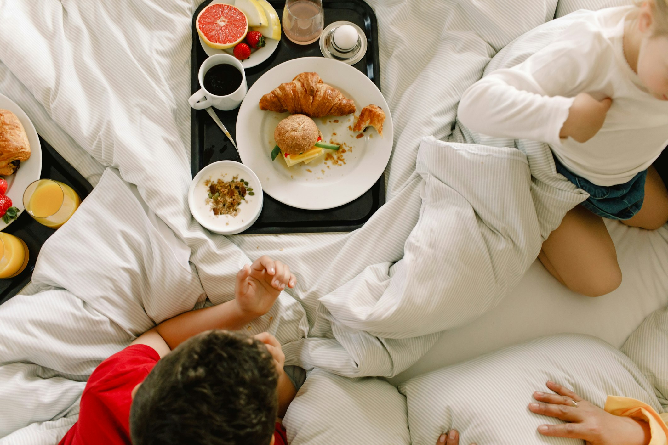 Directly above shot of family having breakfast on bed in hotel - stock photo