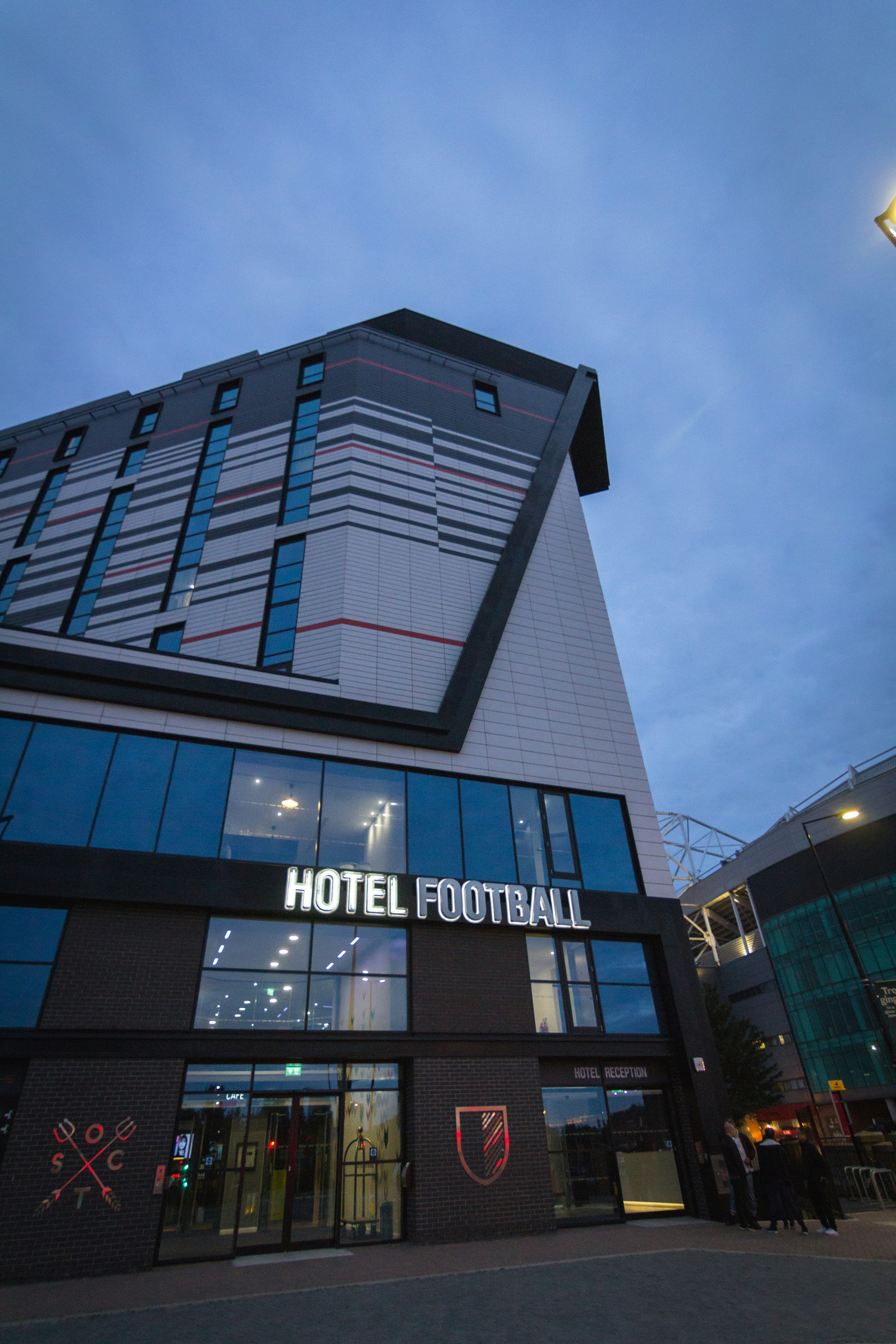 An entrance to the Hotel football, in Manchester. A group of three people are standing to the left