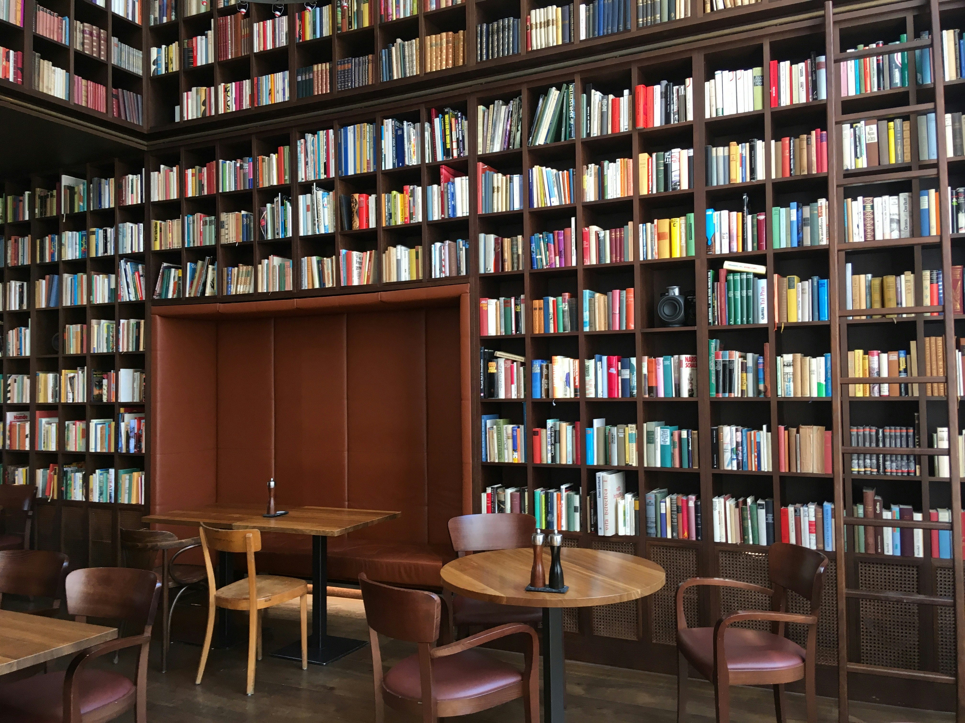 Interiören i B2:s vinbibliotek: de höga väggarna är täckta med rader och rader av bokhyllor i mörkt trä, med en sittalkov inbyggd i dem på marknivå;  Det finns ytterligare träbord och stolar i mitten av rummet.