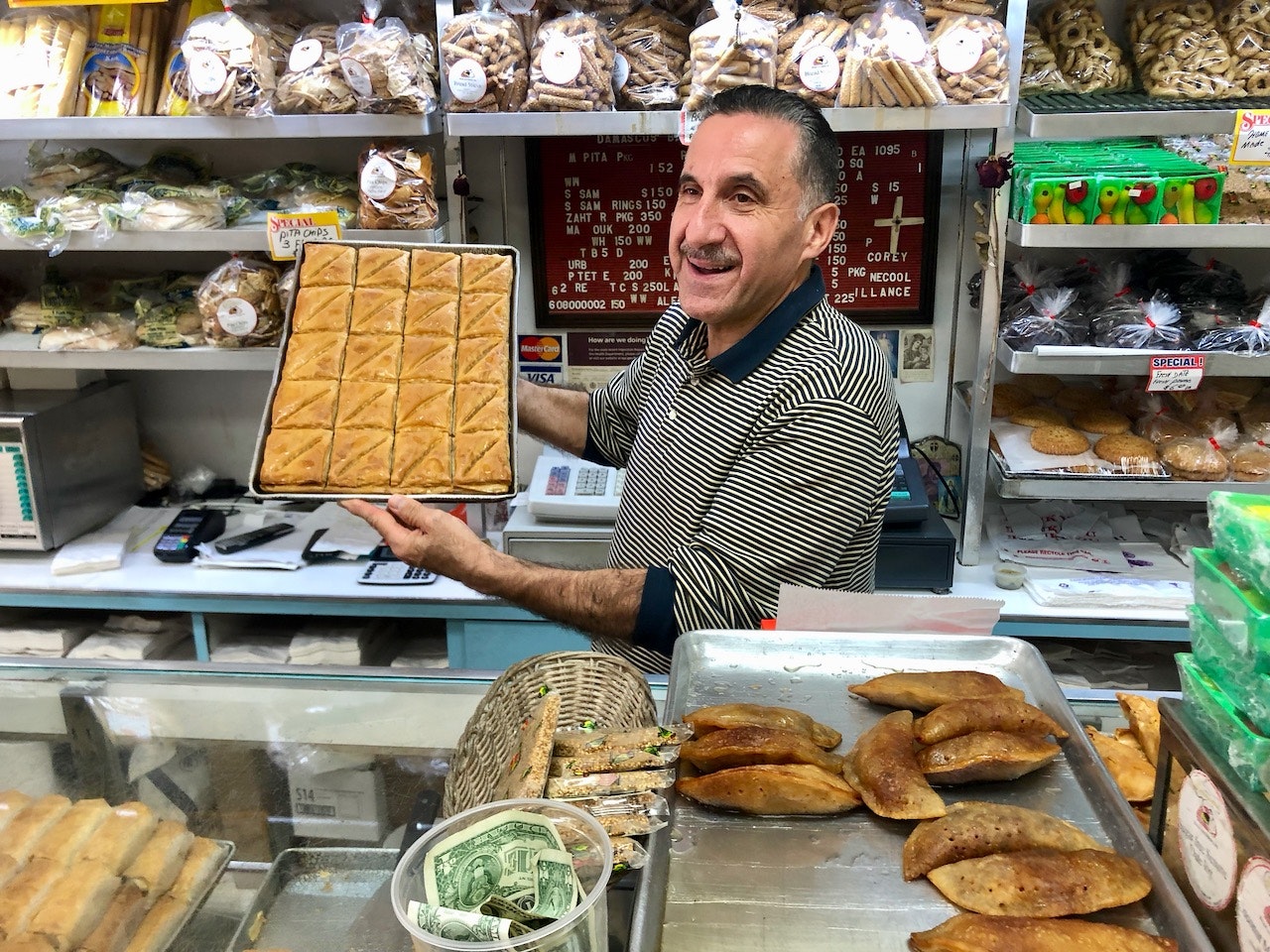 Gus Matli holding up a tray of fresh-baked baklava at Damascus Bakery in Brooklyn