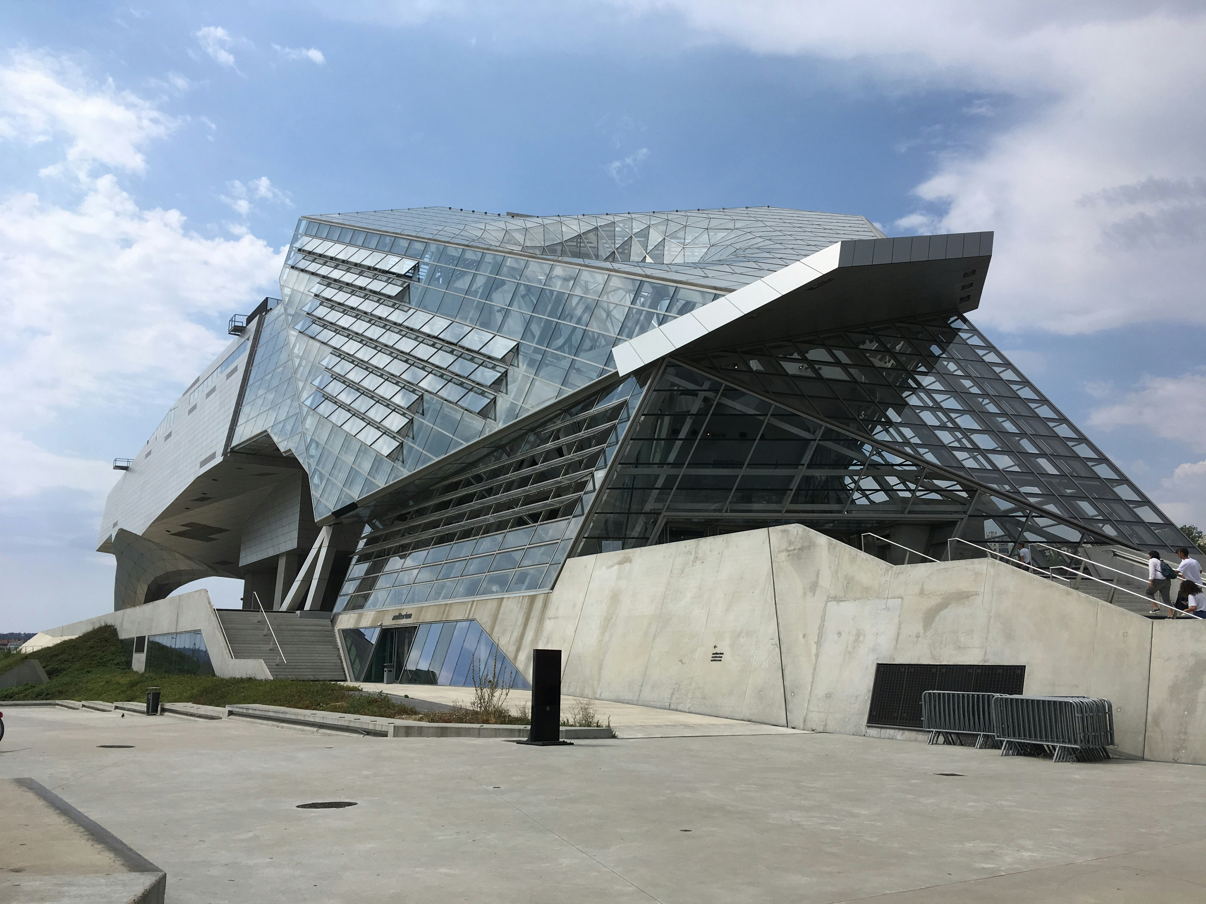 The exterior of the Musée des Confluences is made of glass and steel with a concrete ramp up to the entrance. The building has an unusual shape, a little like a crouching animal