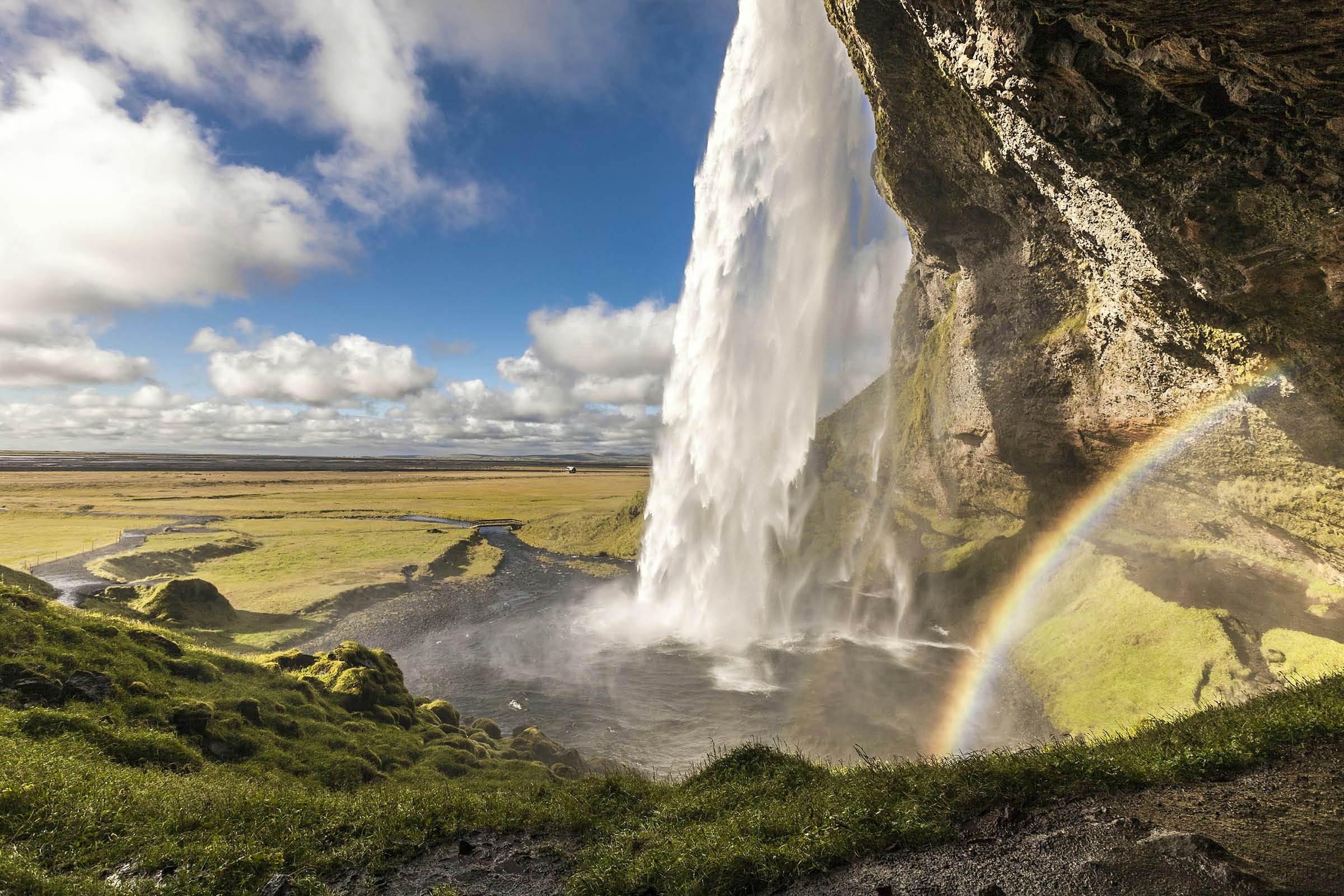 A rainbow springs from the mist under Seljalandsfoss waterfall