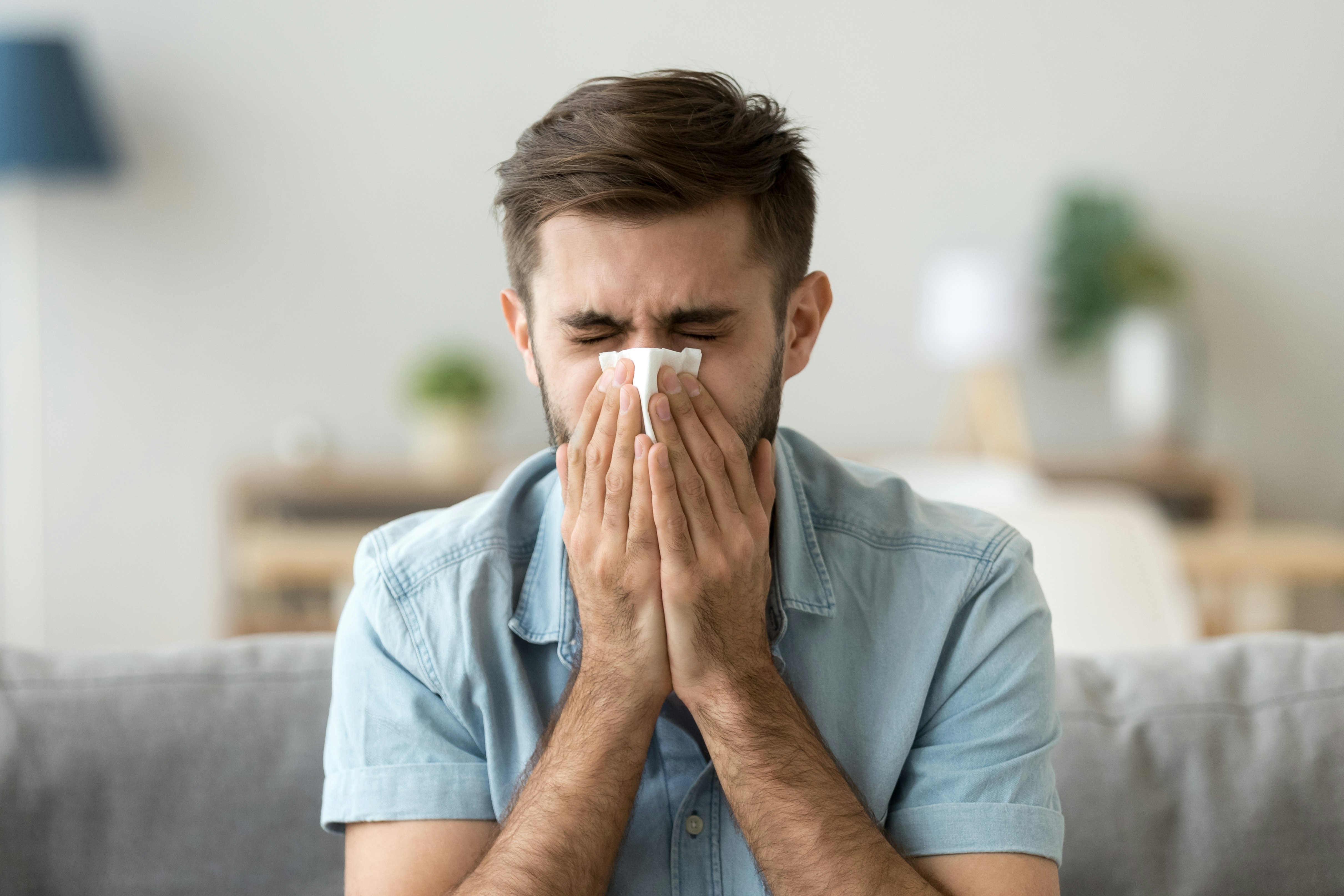 A man is sneezing into a tissue 