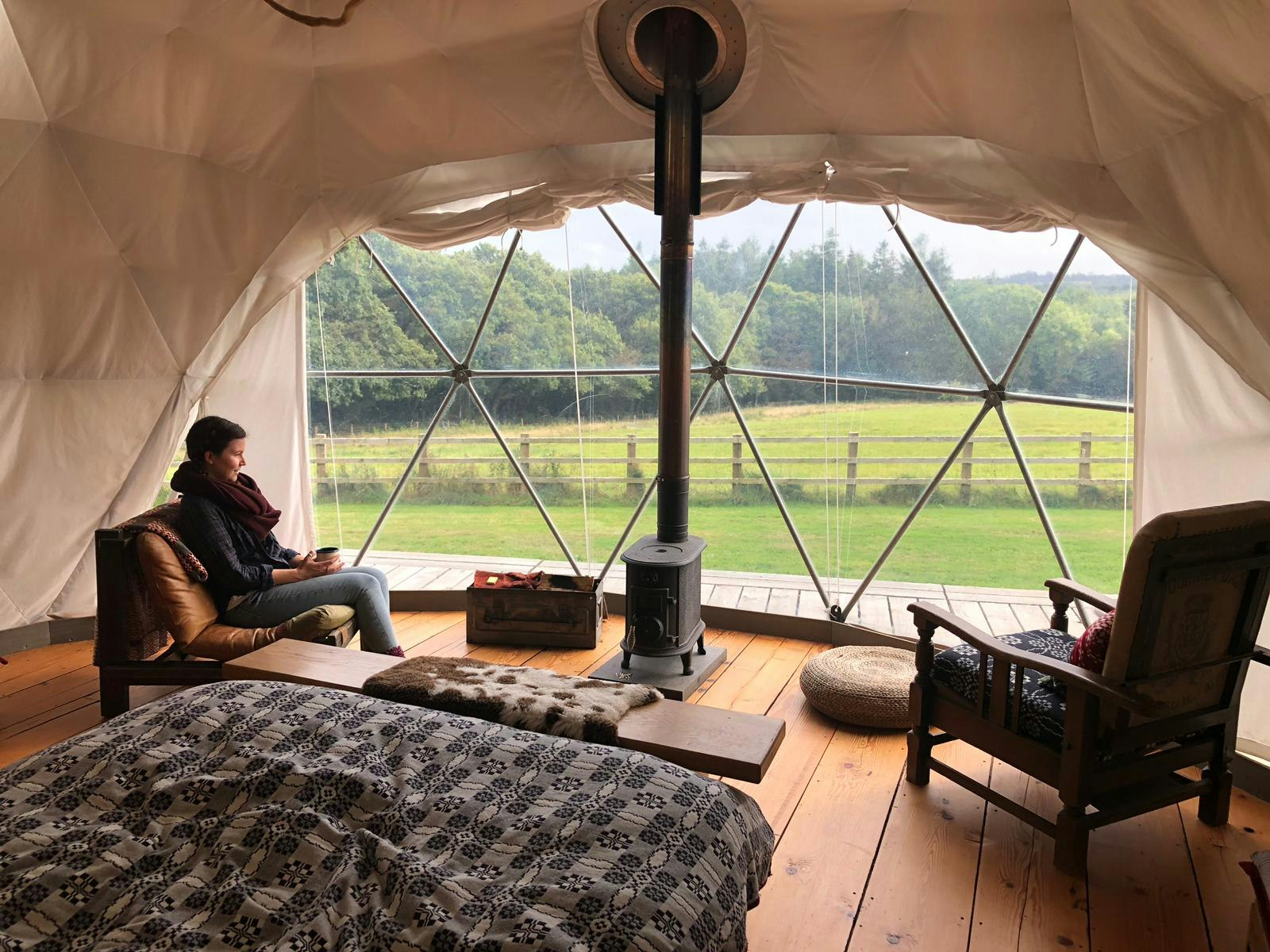 Emma sits inside her geodesic dome looking out at the countryside through the glass wall.