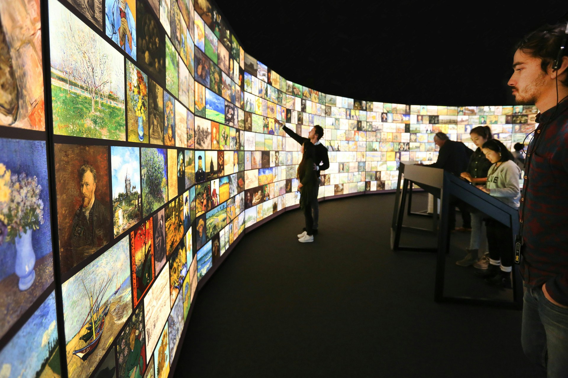 Installation view of Meet Vincent van Gogh - people looking at a wall of screens with Van Gogh's artwork