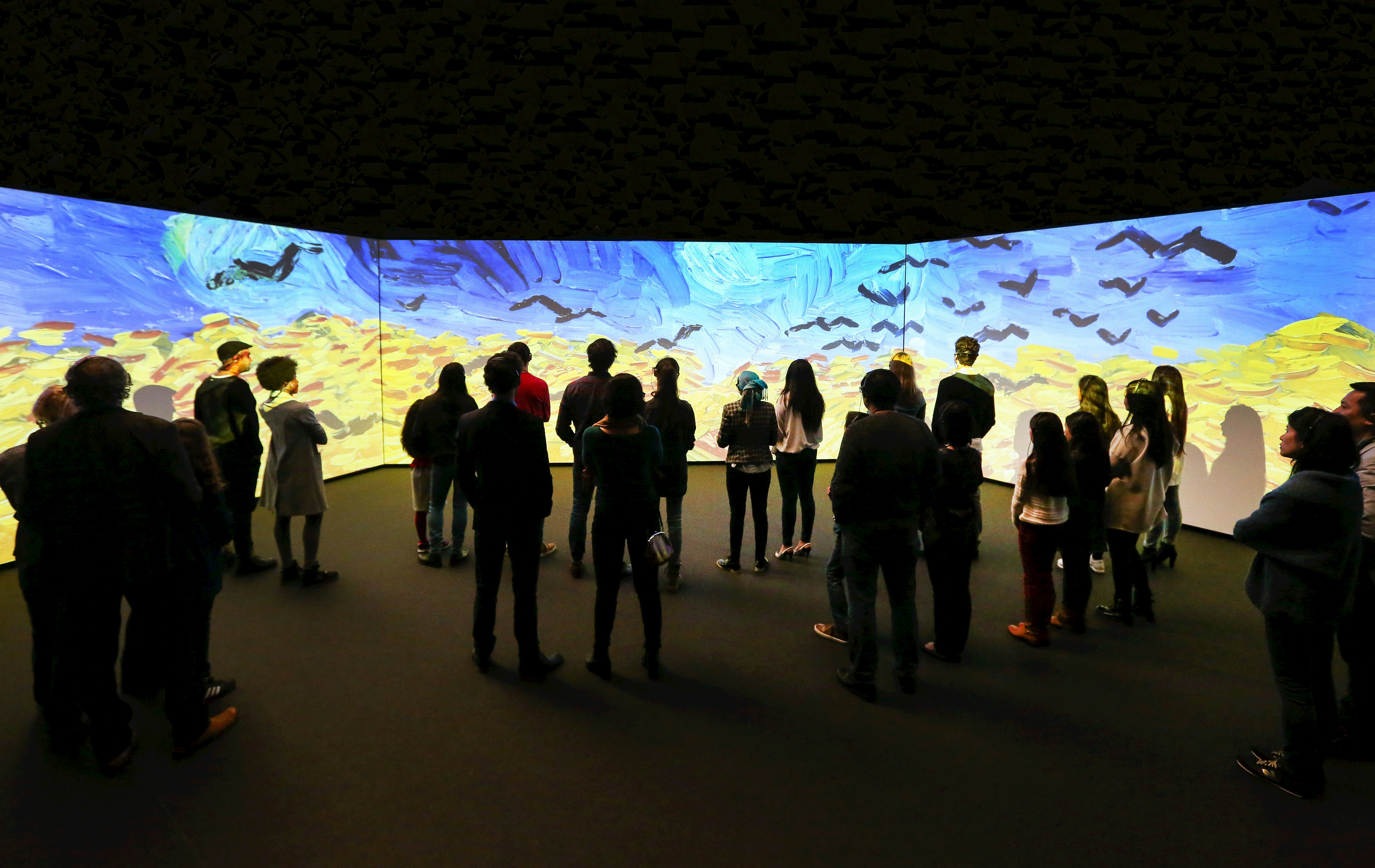 People in front of screens showing a Van Gogh painting