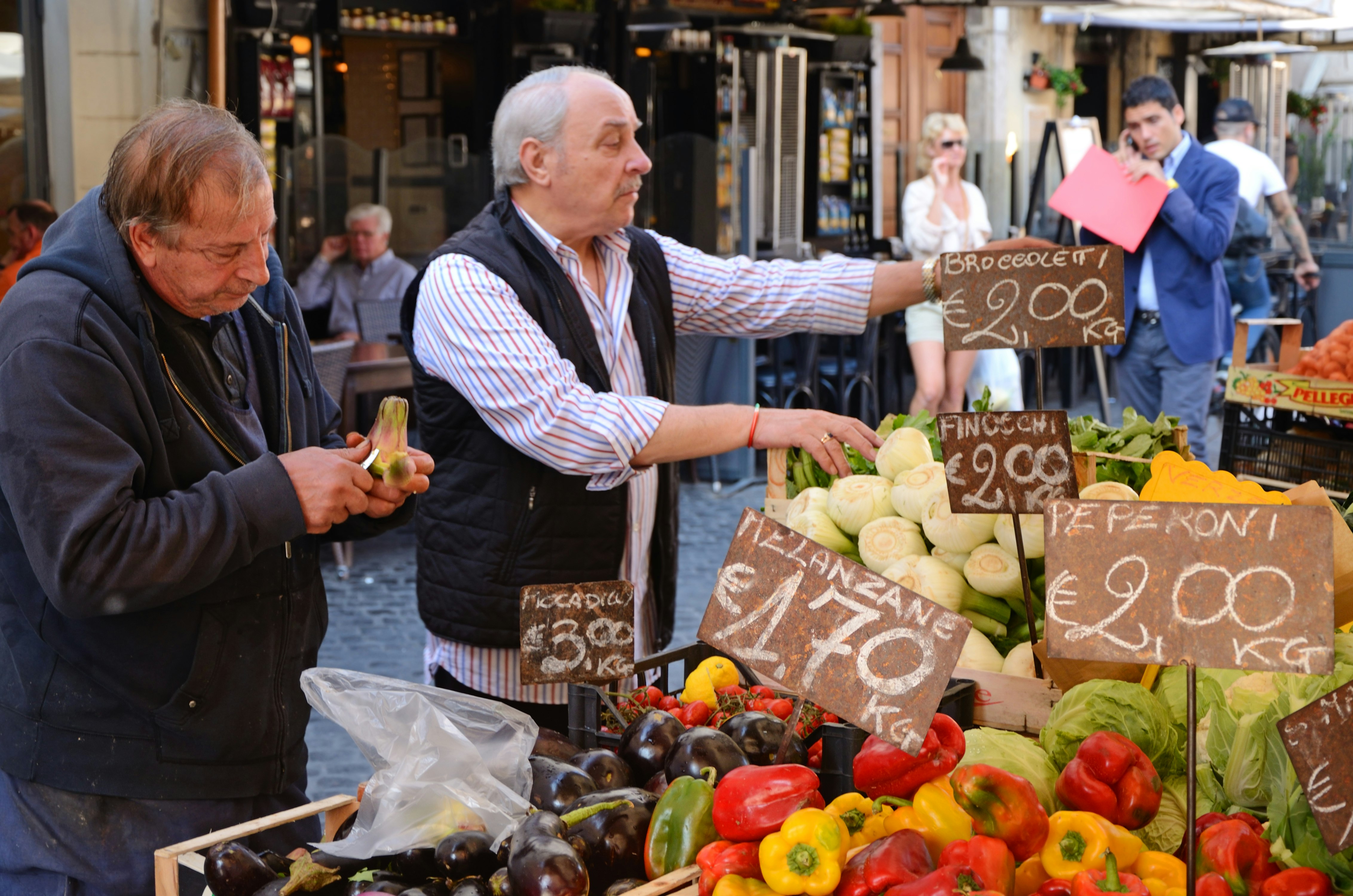 Two vendors selling fresh produce at Campo dei Fiori farmer's market in Rome.