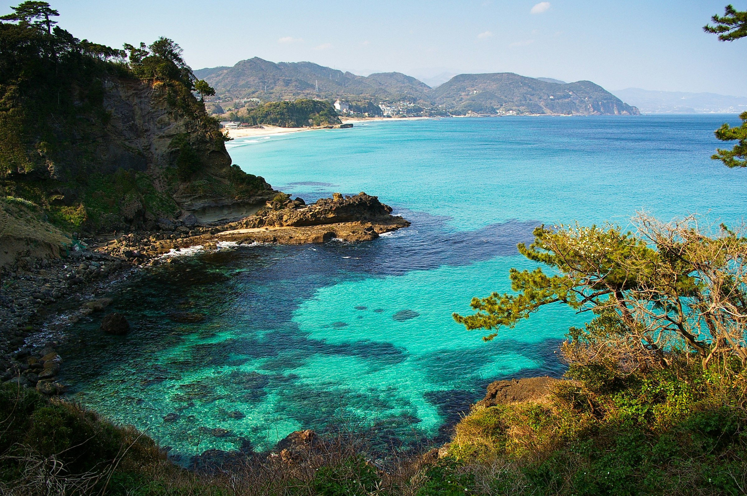 Turquoise water along a craggy, palm-flanked seaboard