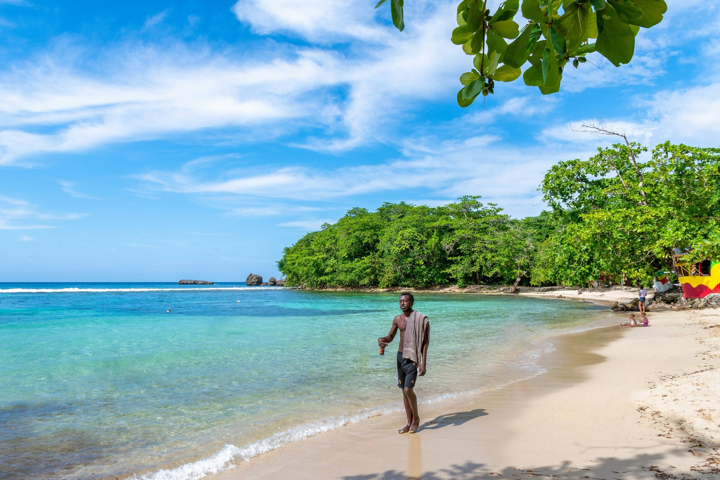 Man walking along Jamaica’s Winifred Beach on a sunny day. 