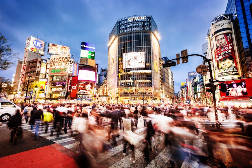 Lång exponering av fotgängare som korsar den berömda Shibuya Crossing i Tokyo i skymningen.